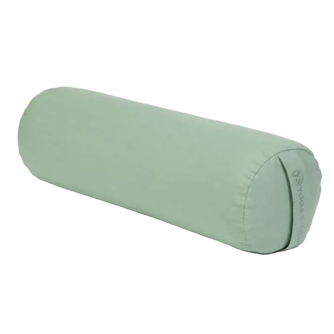 Green yoga bolster on a light gray background