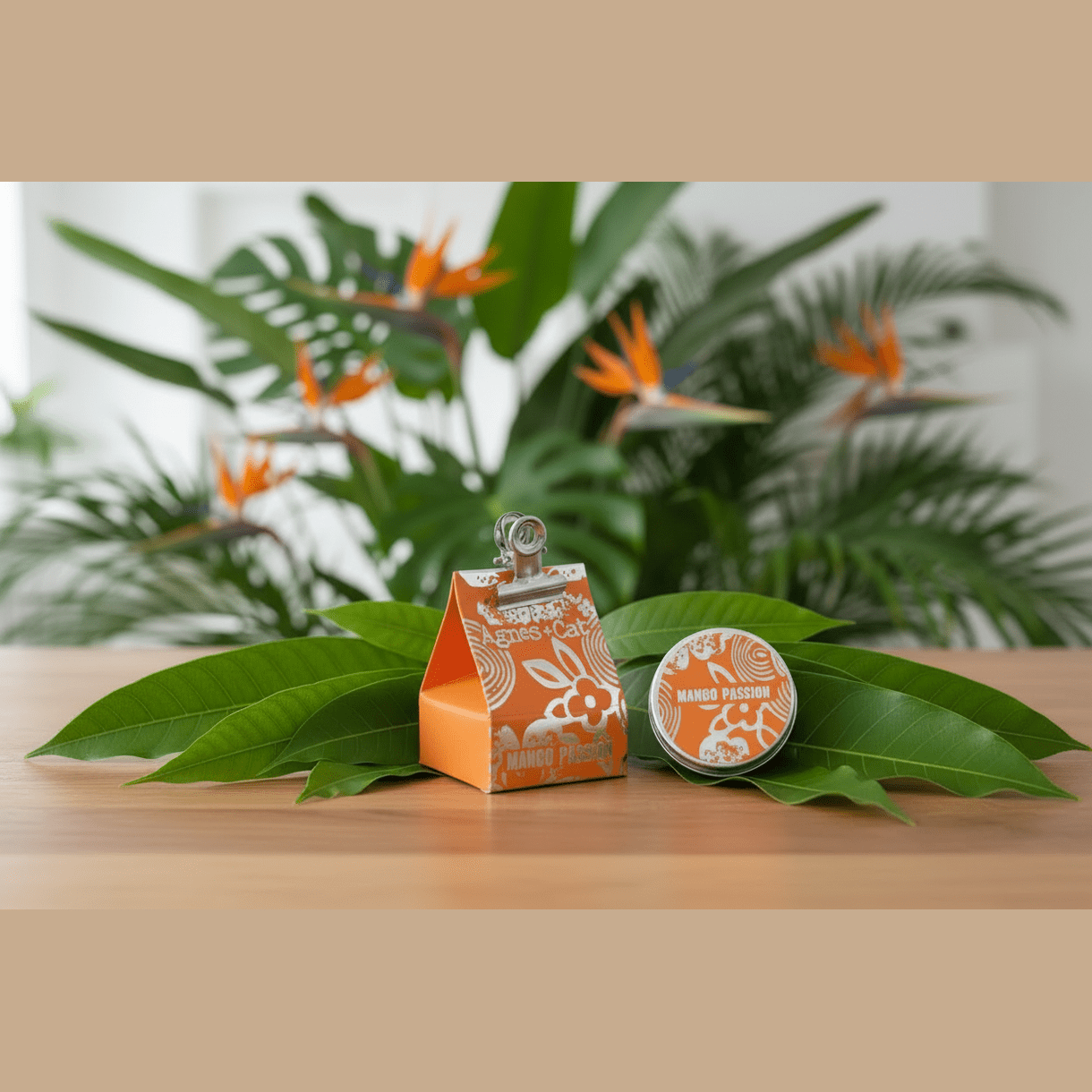 Orange and white Natural lip balm packaging with a clip on a wooden surface with green leaves and plants in the background