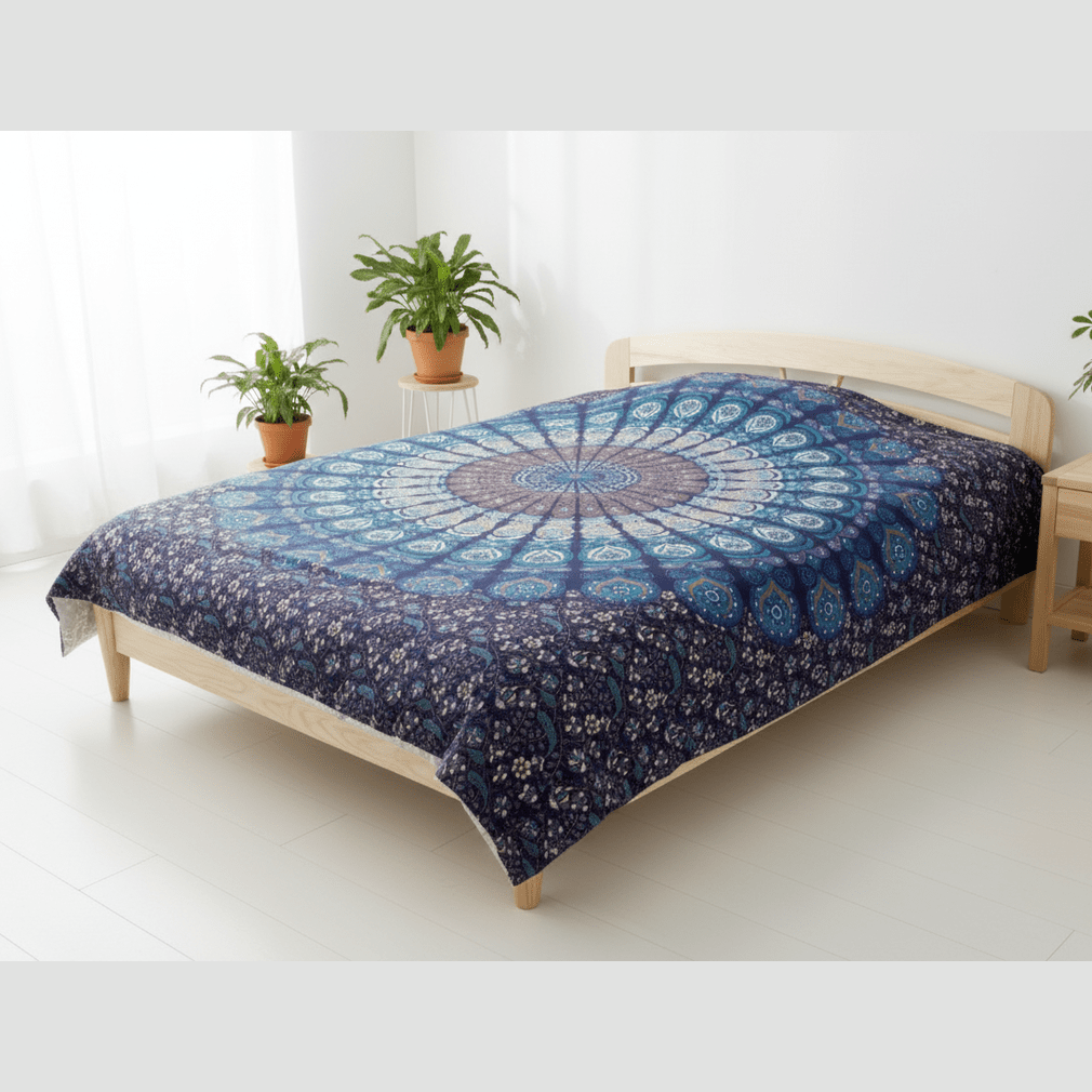 Bed with a blue mandala patterned comforter in a bright room with plants.