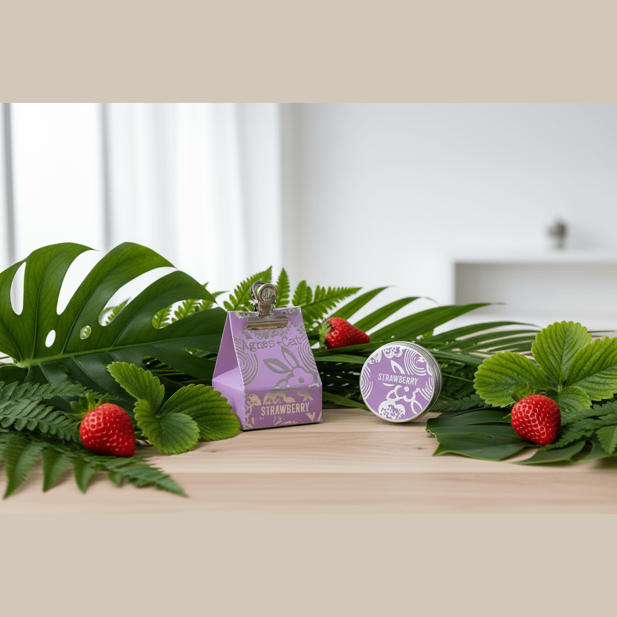 Natural lip balm with a strawberry design on a wooden surface with green leaves and strawberries.