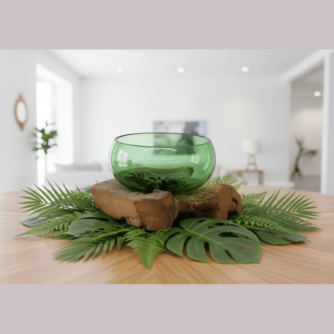 Green glass bowl on a wooden log with fern leaves in a room setting