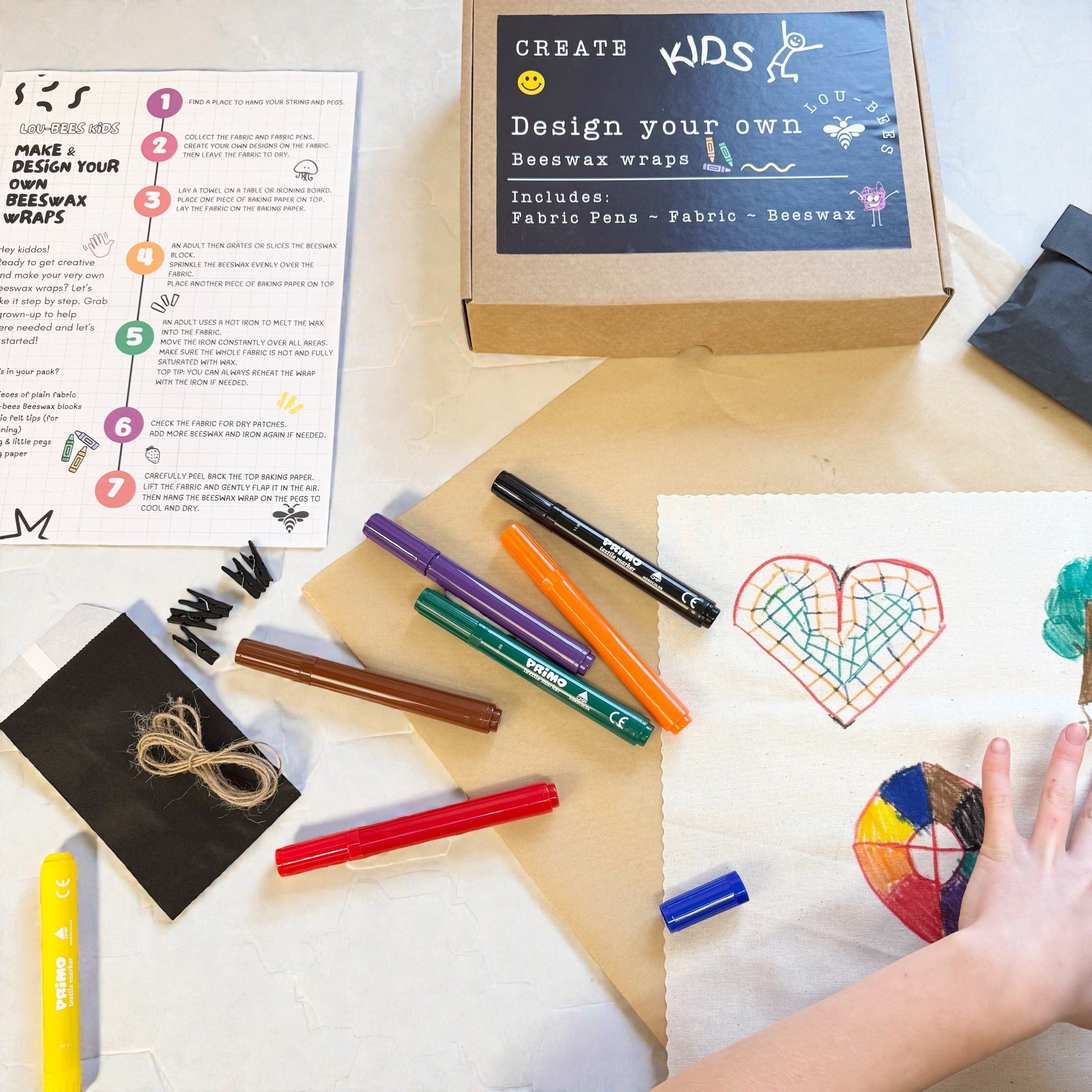 Children's craft kit with markers, fabric, and a heart design on paper.