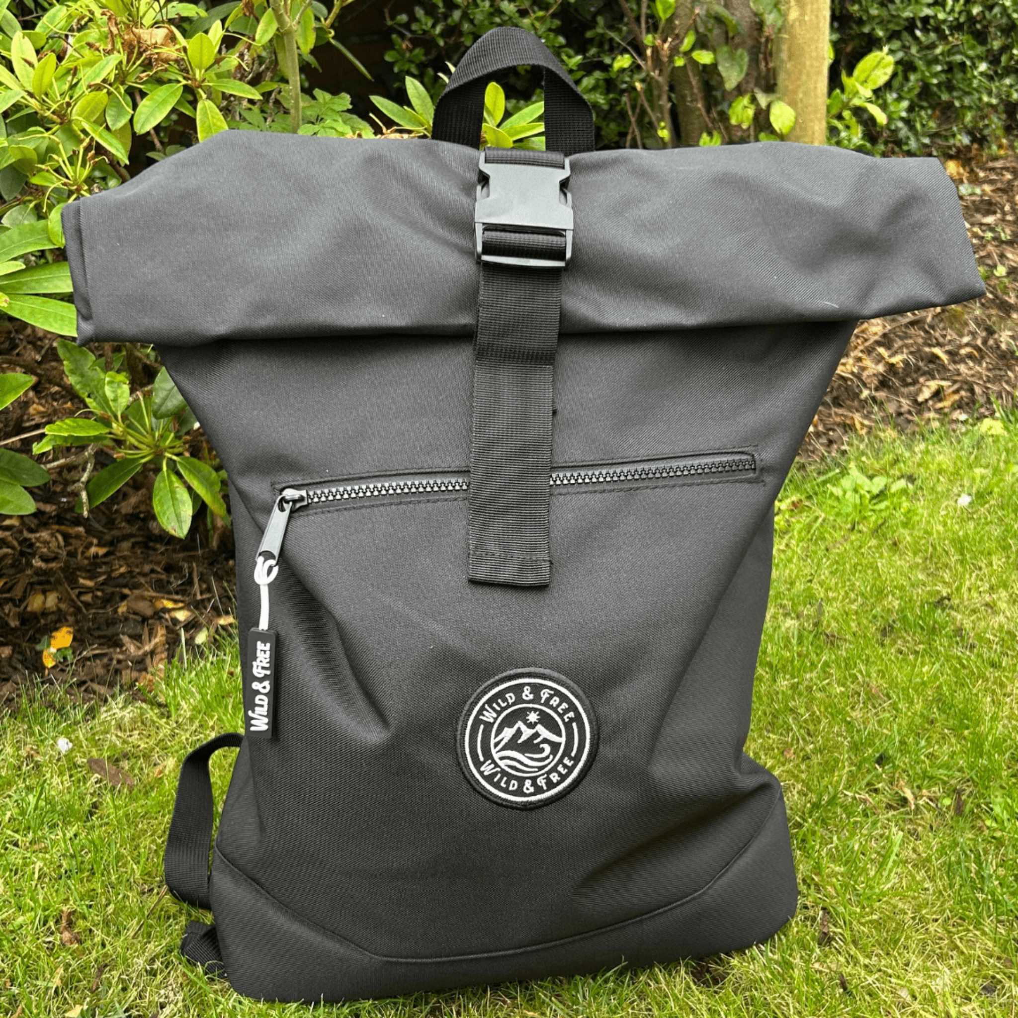 Green roll-top backpack with a visible brand logo on grass