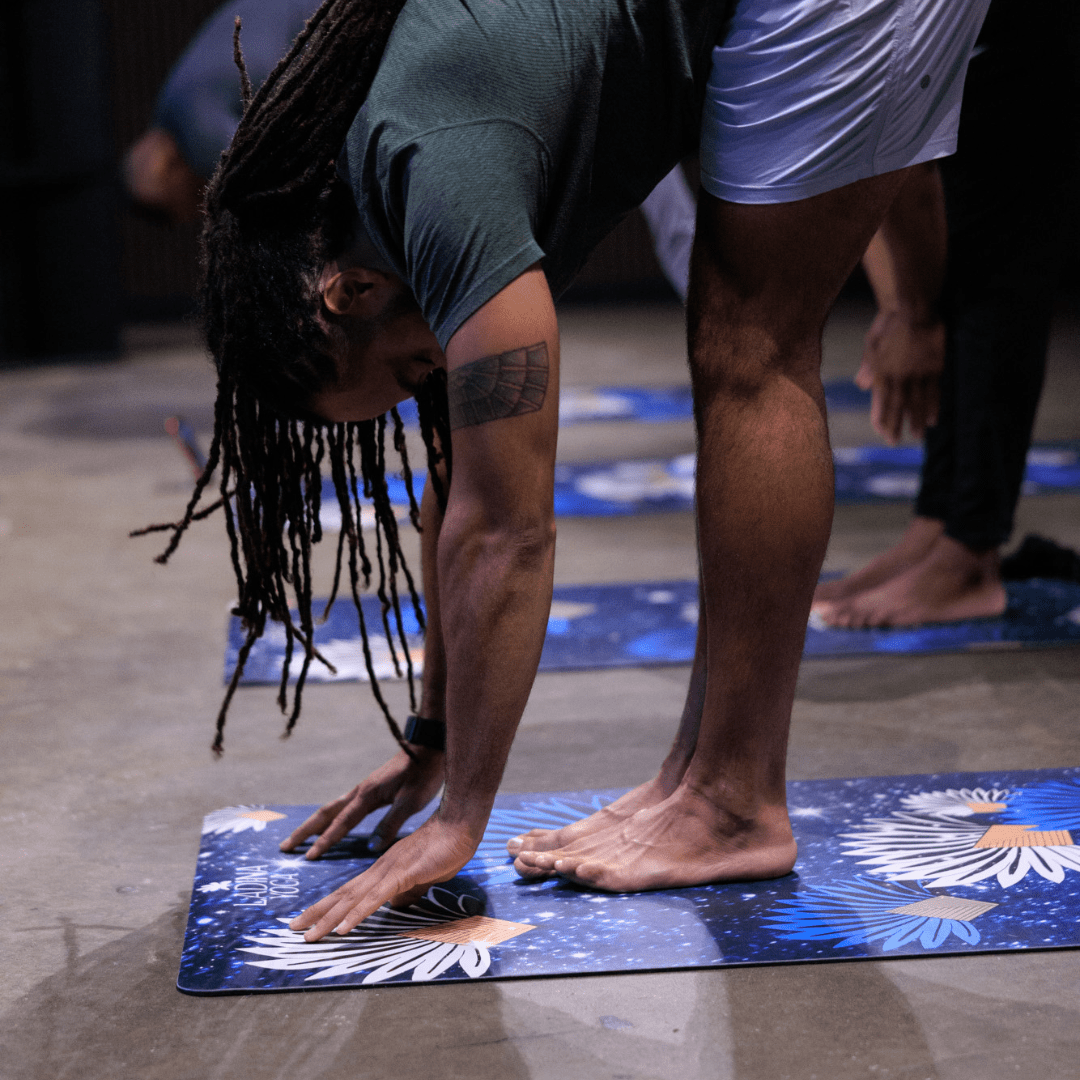 Person practicing yoga on a blue mat with others in the background