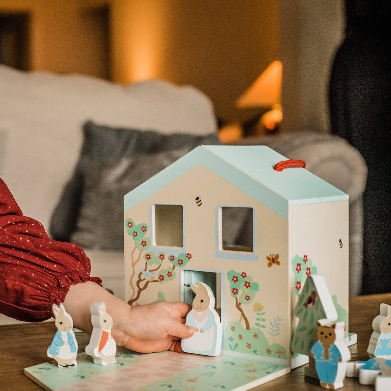 Children's wooden house toy with small figures on a table