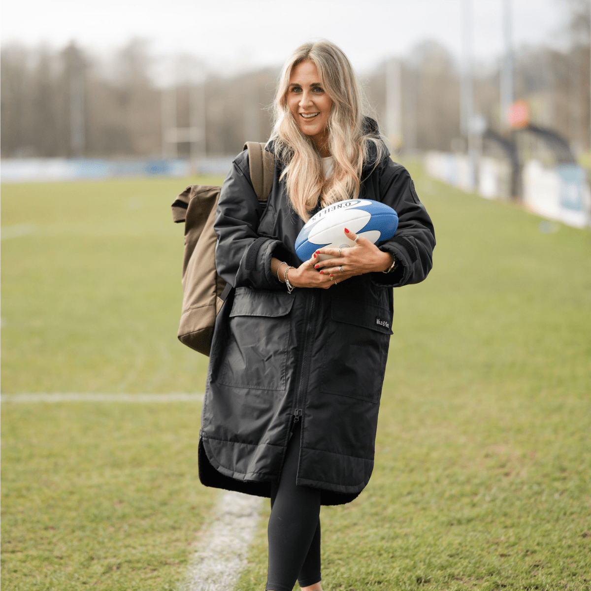 Woman holding a rugby ball on a grassy field