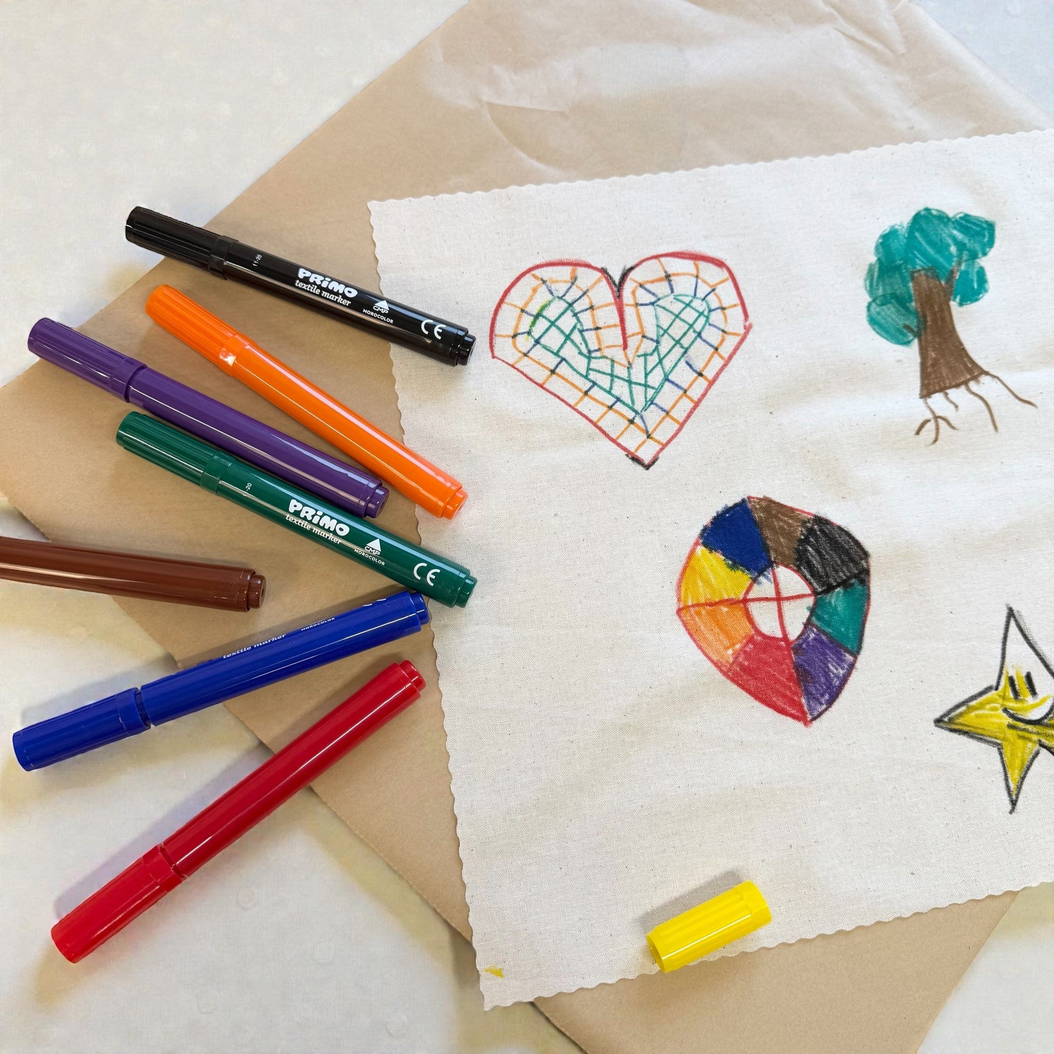 Colorful markers and children's drawings on a white surface