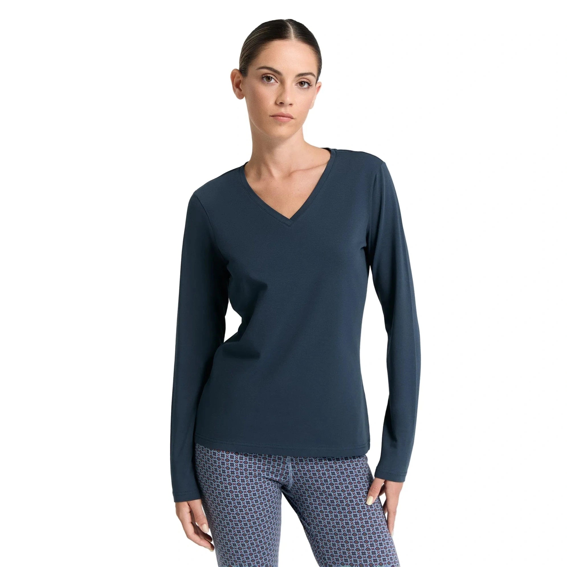 Woman wearing a navy long-sleeve top and patterned pants on a white background