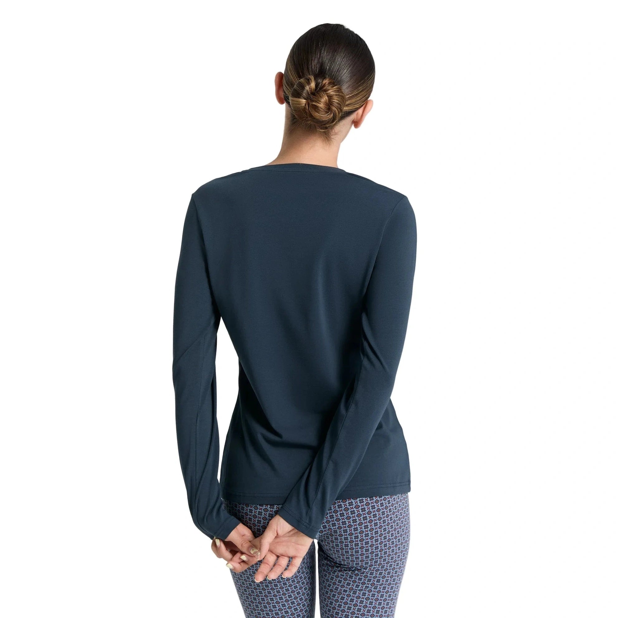 Person wearing a navy long-sleeve top and patterned leggings on a white background