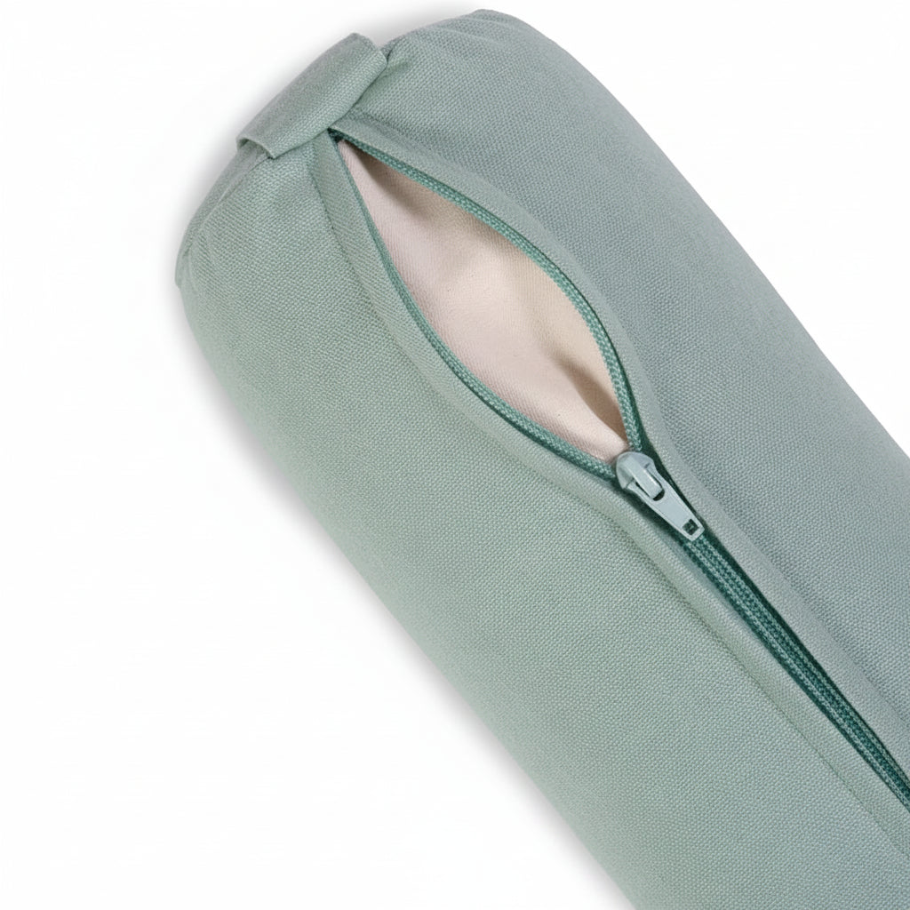 Close-up of a sage green mini yoga bolster sleeve with a partially unzipped zipper revealing a light beige interior lining, set against a clean white background.