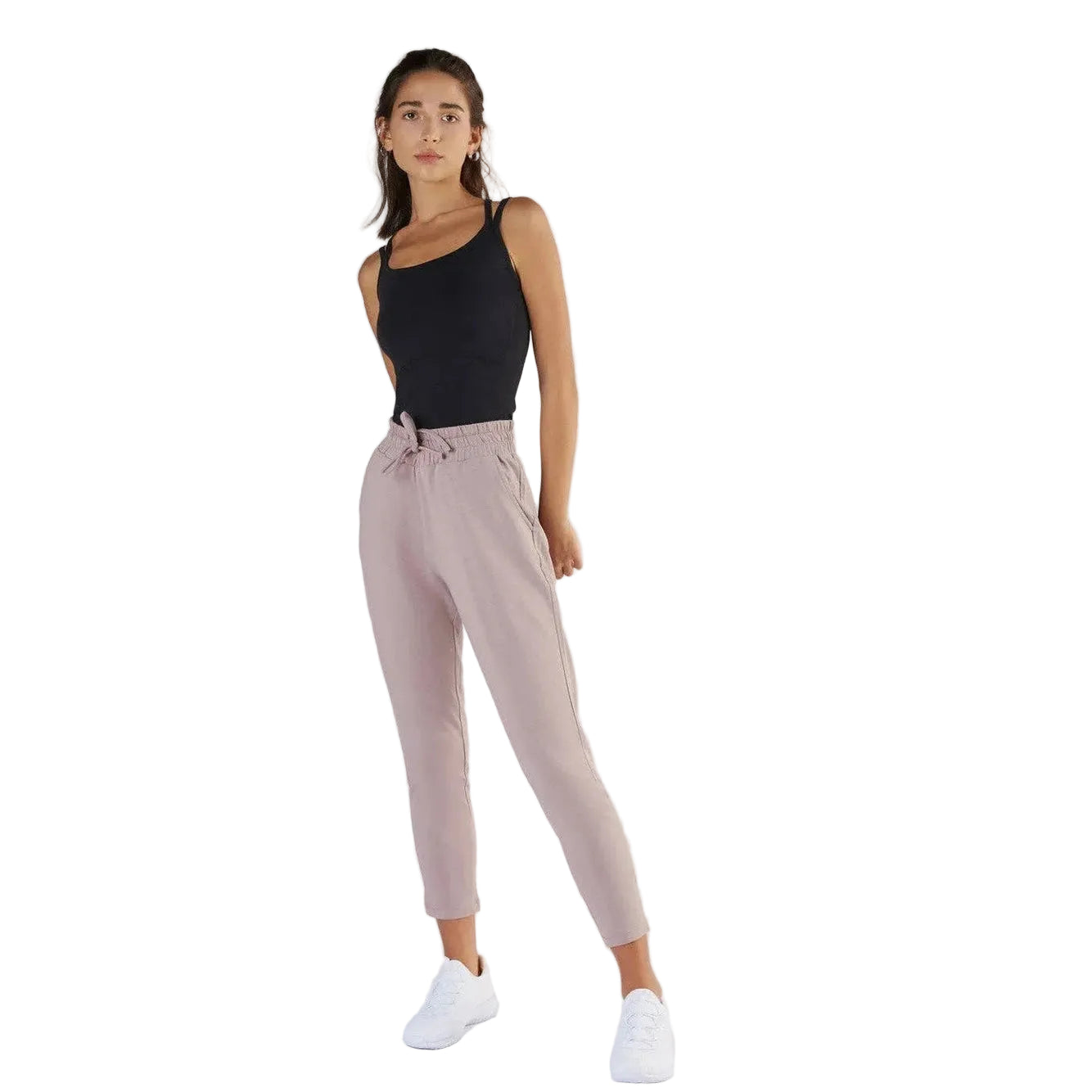 Woman wearing a black tank top and beige pants on a white background