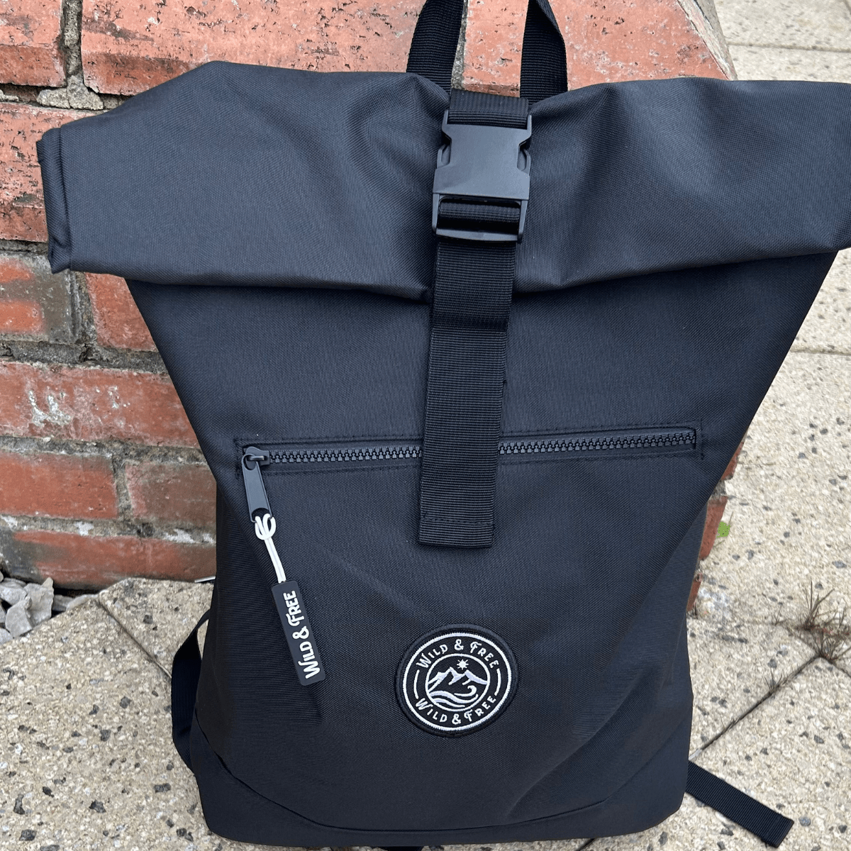 Black backpack with a visible brand logo against a brick wall background