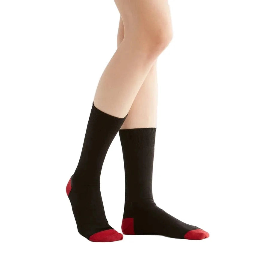 Black socks with red toes and cuffs worn by a person on a white background