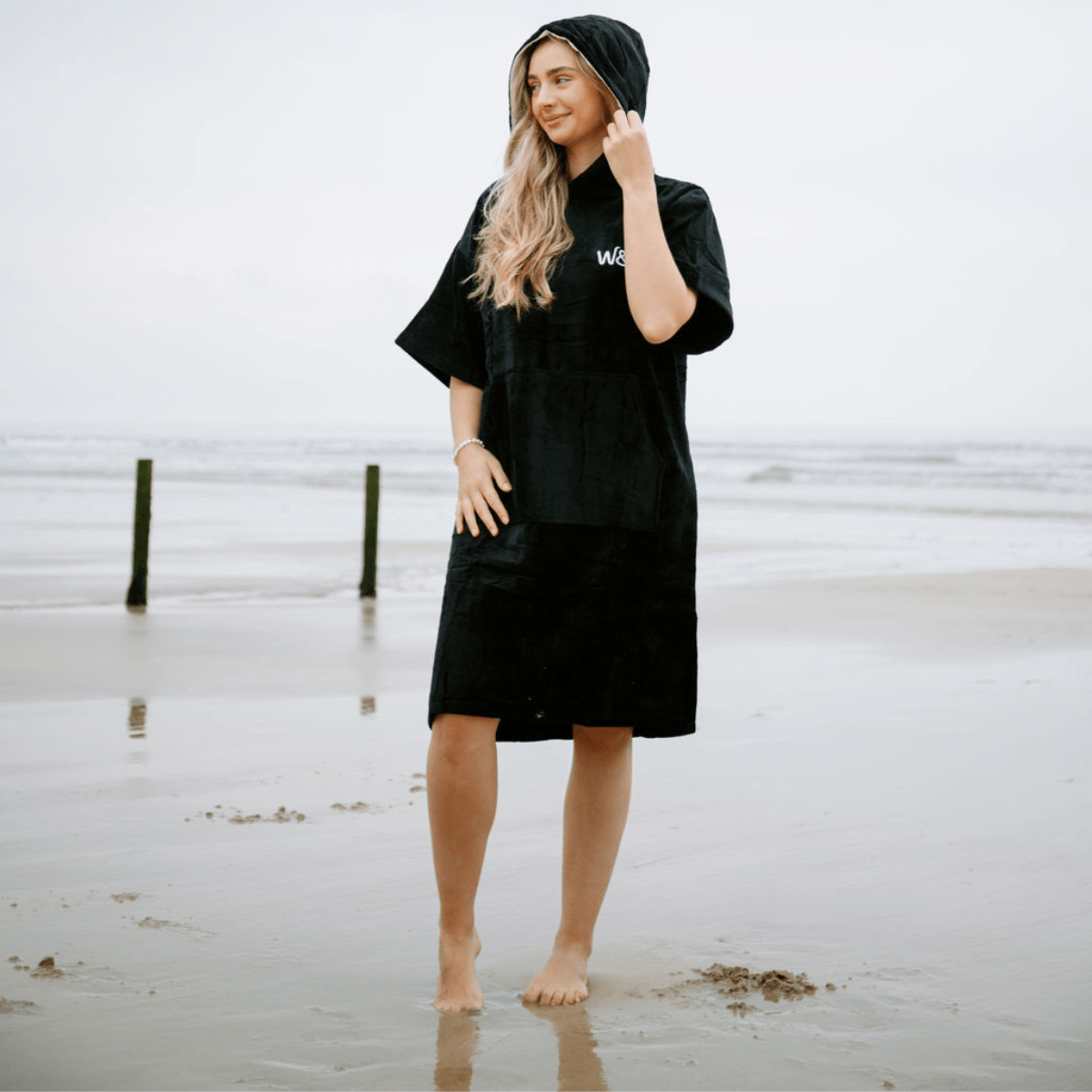 Woman wearing a black hooded towel on a beach