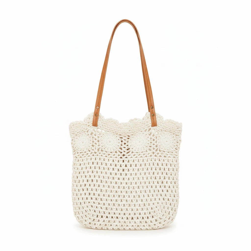 An off-white crocheted tote bag with scalloped lace trim and tan shoulder straps, shown against a plain white background.