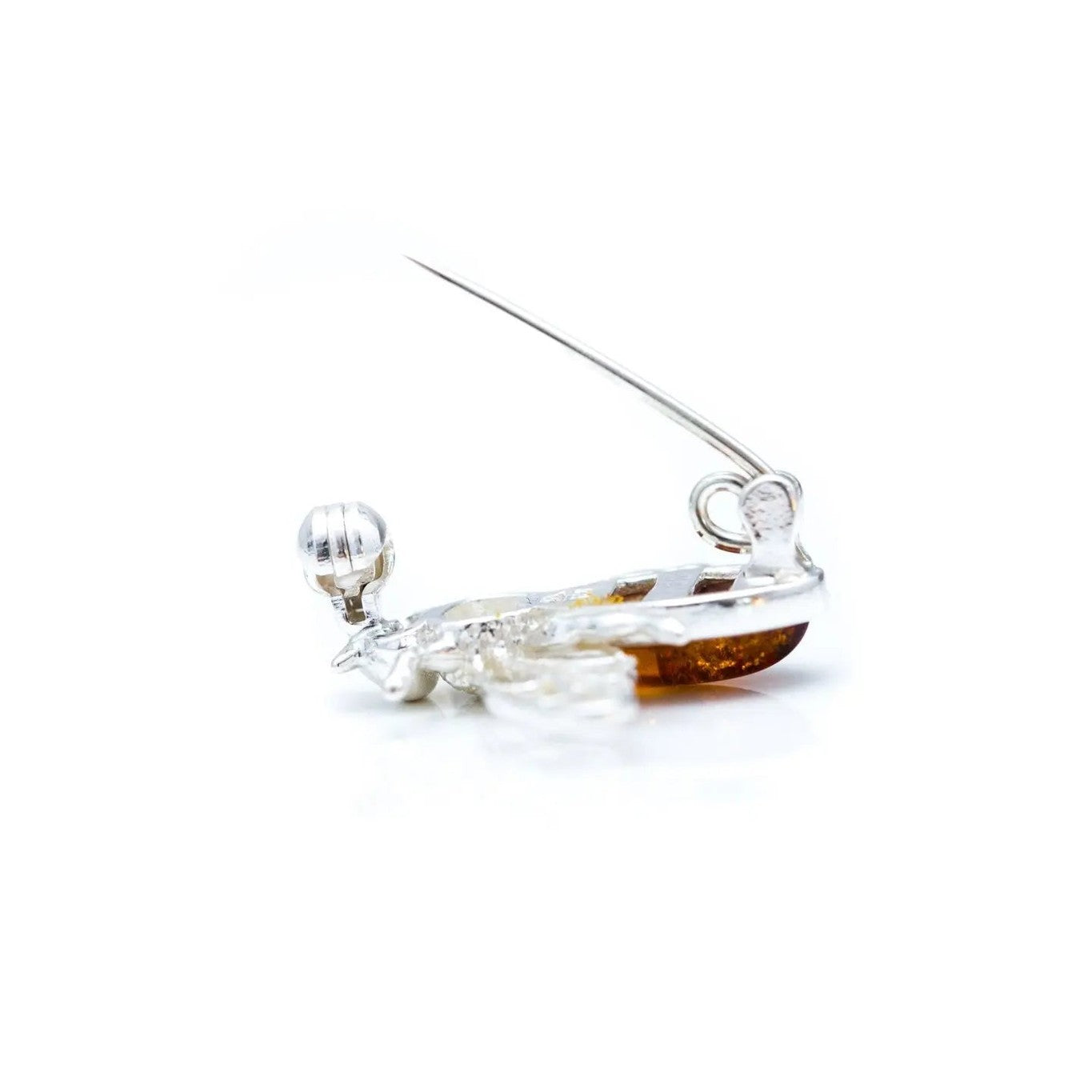 A silver bee brooch with amber-colored gemstones on a white background