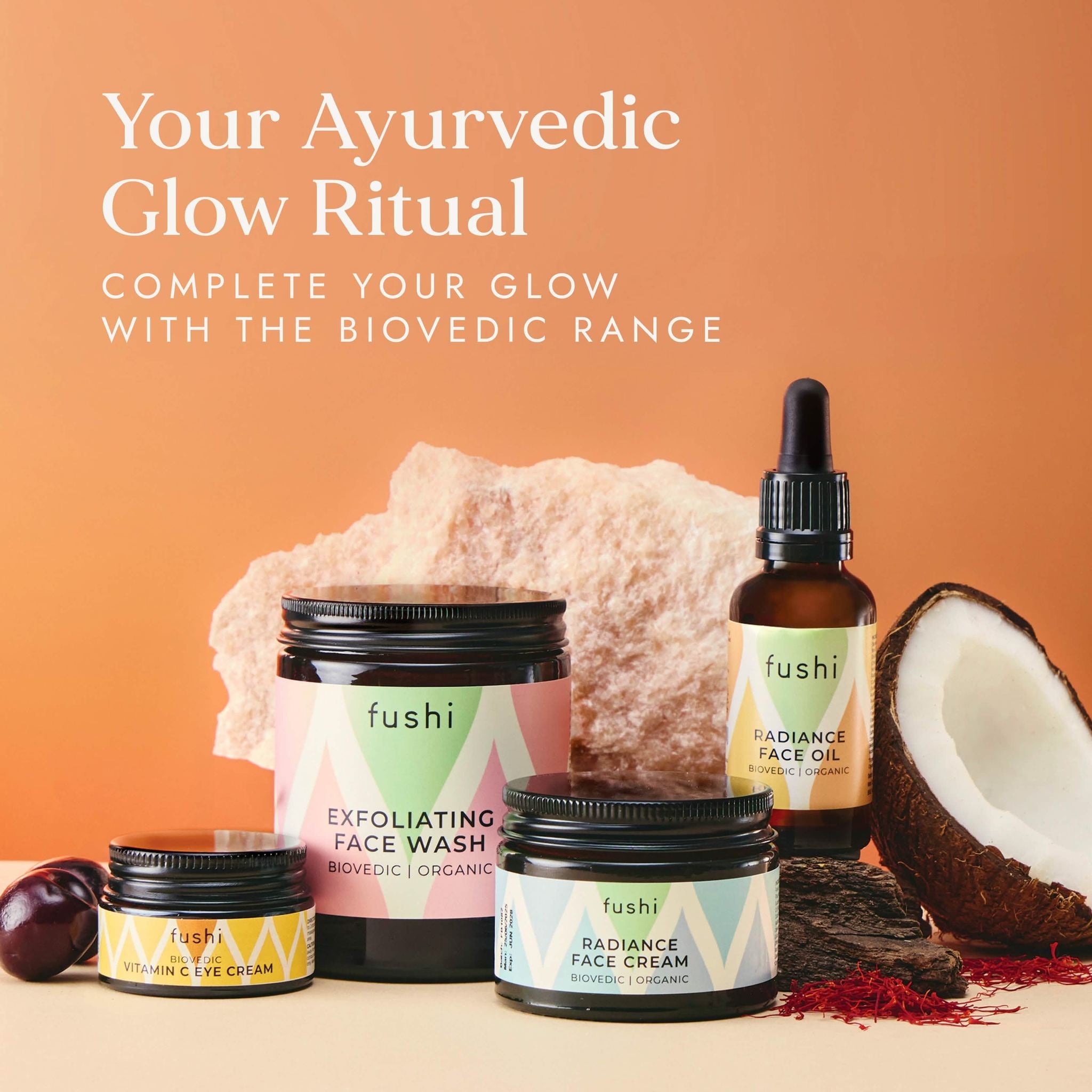 Fushi Ayurvedic skincare products with a coconut, rock, and plum on an orange background.