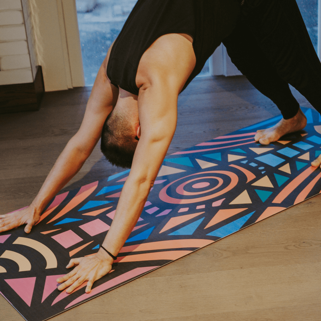 Person practicing yoga on a colorful mat indoors