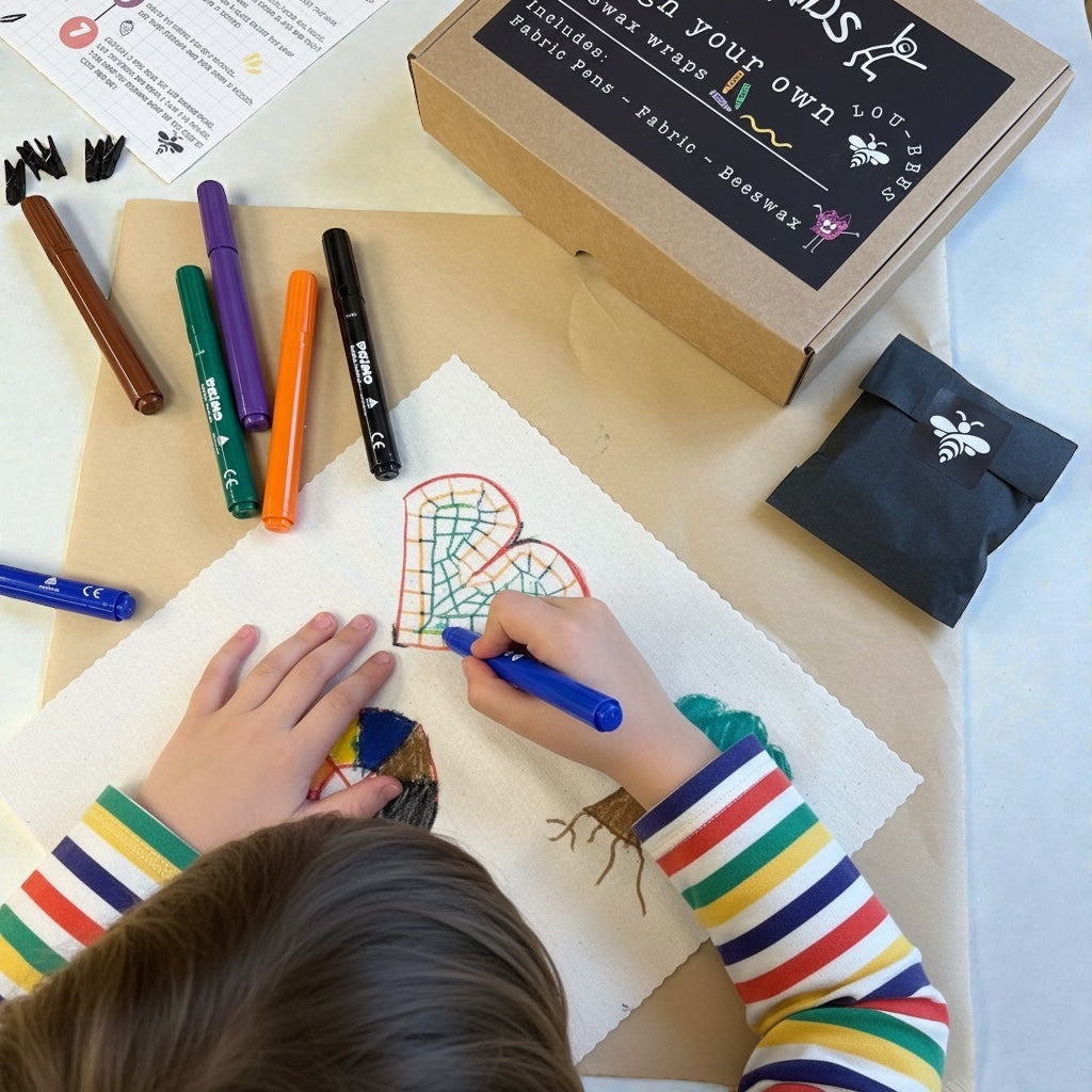 Child coloring a design on fabric with markers, surrounded by craft supplies.