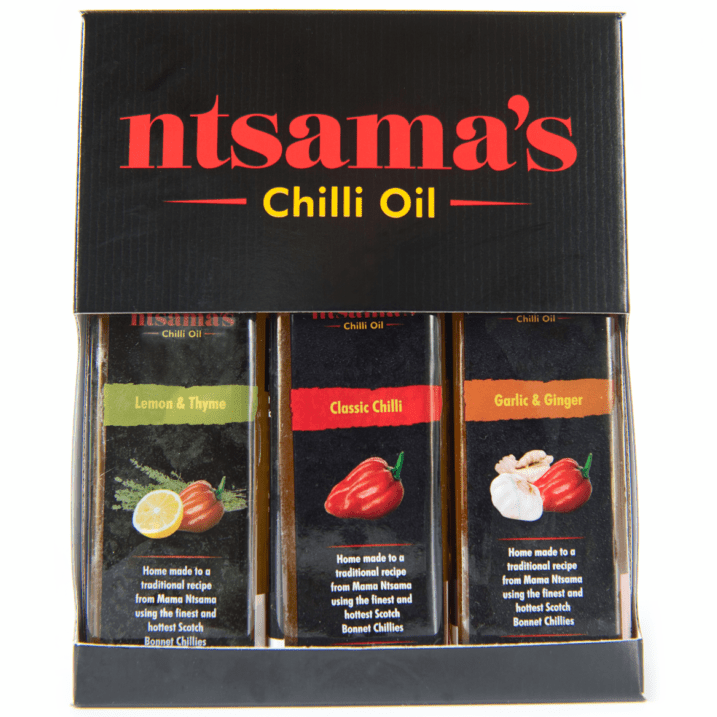 A boxed set of Ntsama's Chilli Oil containing three glass bottles: Lemon & Thyme, Classic Chilli, and Garlic & Ginger, presented in a black gift box with red and yellow branding.