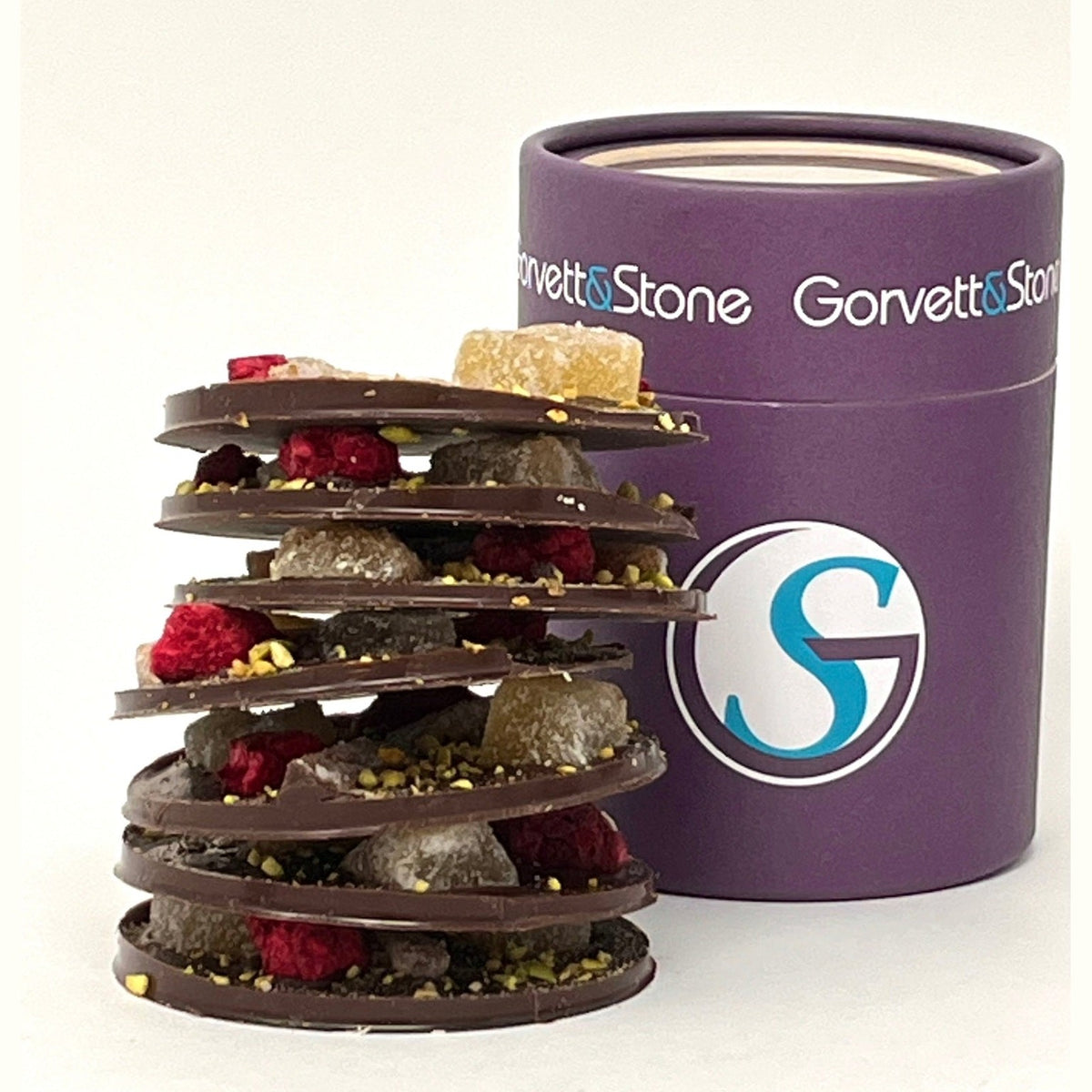 Chocolate tower with various ingredients next to a purple Gorvet&Stone container on a white background