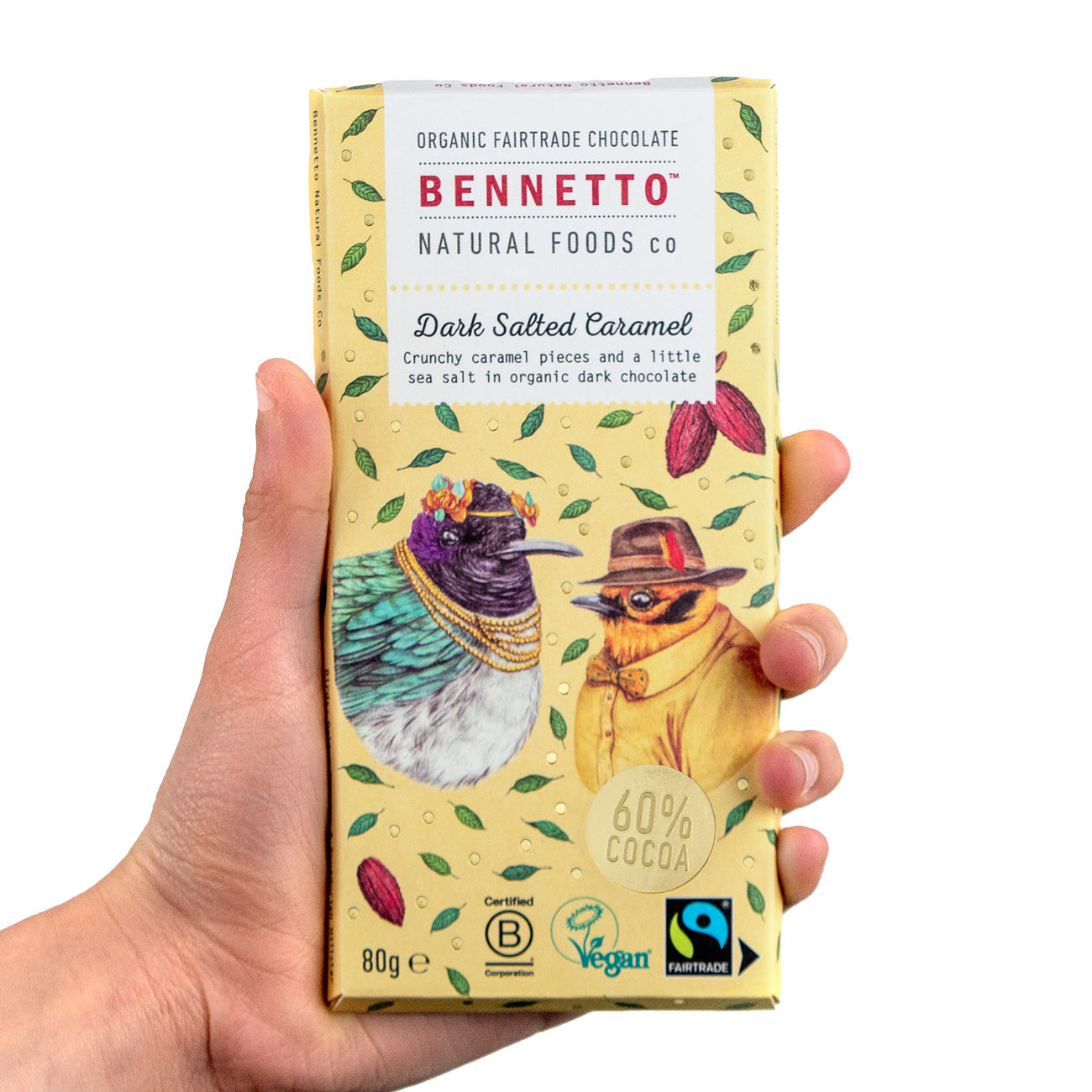 Hand holding a Bennetto chocolate bar packaging with illustrations of birds on a white background
