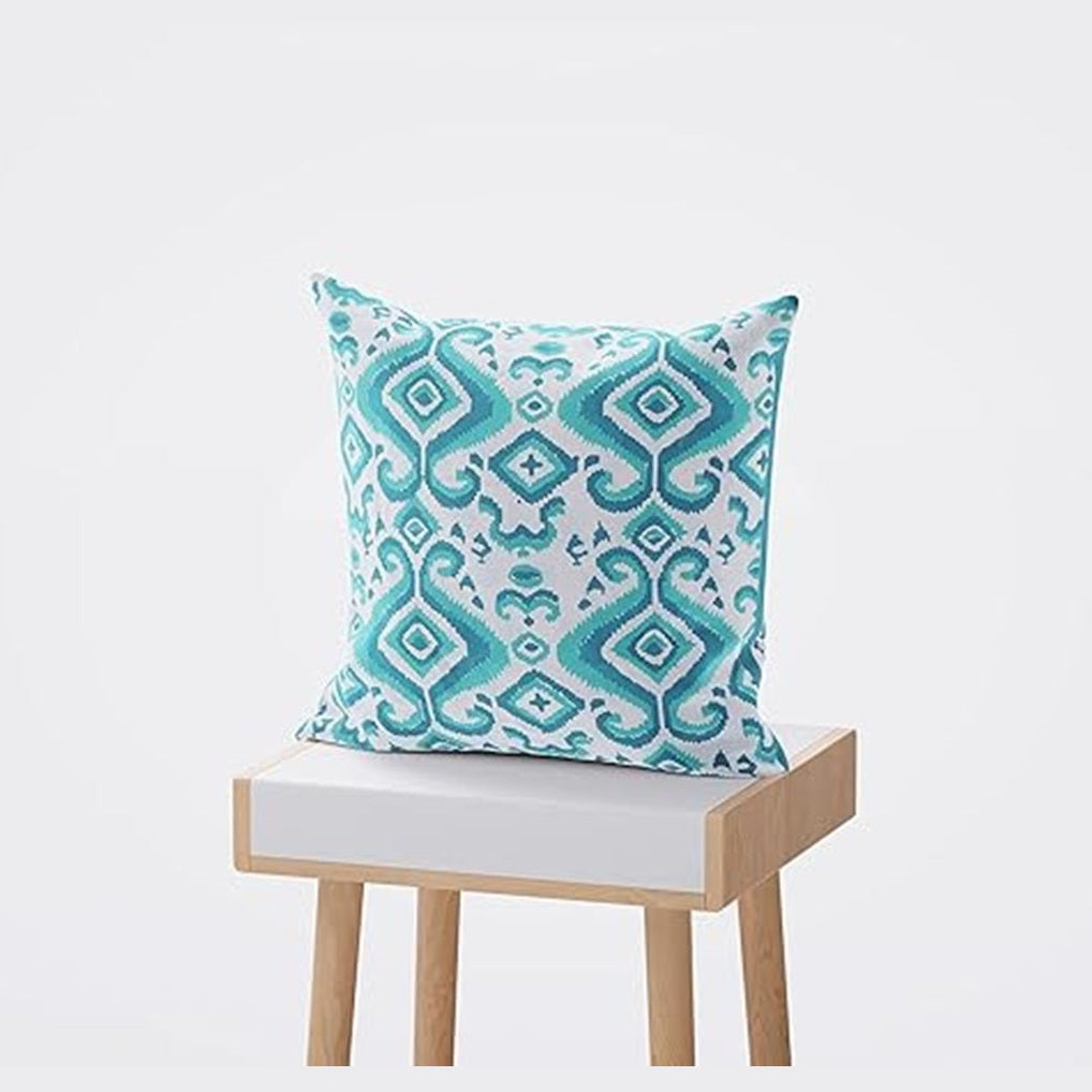 Decorative pillow with a blue and white pattern on a small wooden stool with a white cushion.