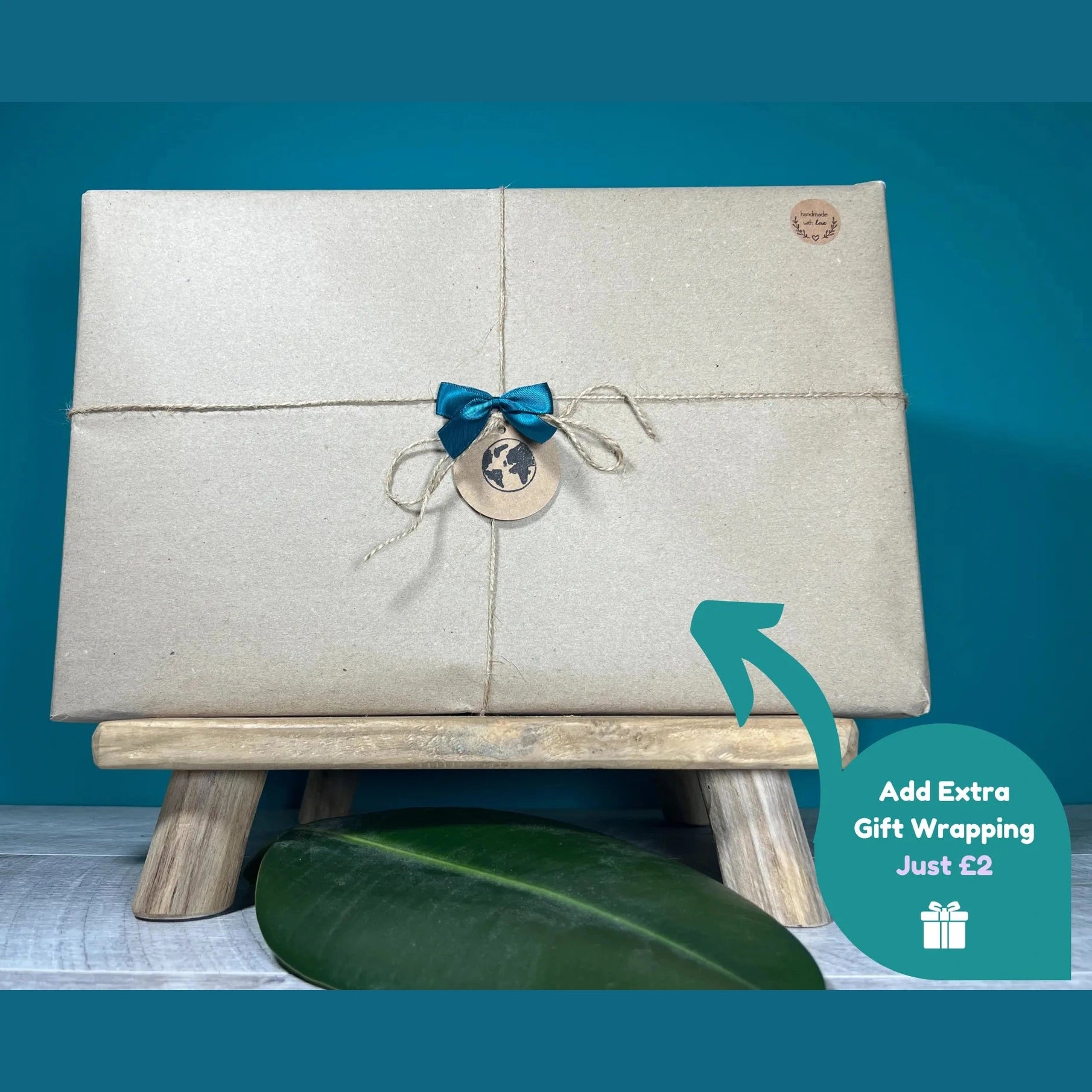Gift box with a blue ribbon and tag on a stand against a blue background, with an option to add extra gift wrapping.