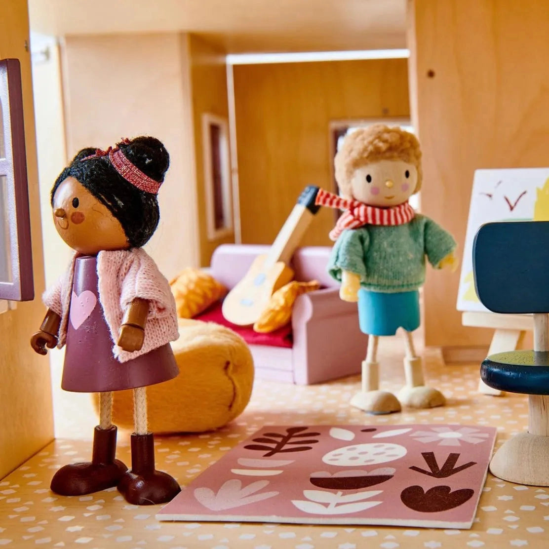 Two dolls in a wooden doll's house with a guitar and a colourful rug.