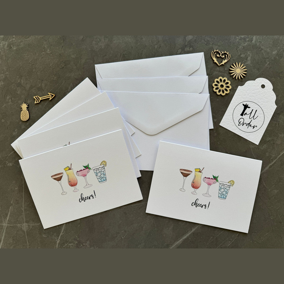 Set of greeting cards with drink illustrations and envelopes on a dark surface.