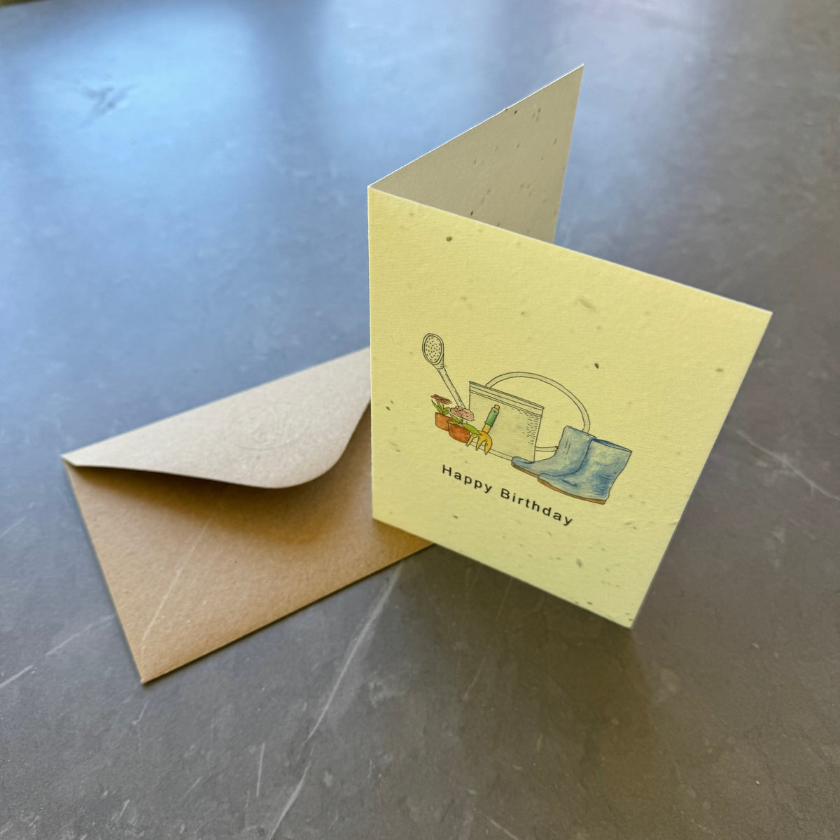 Yellow birthday card with envelope on a metallic surface