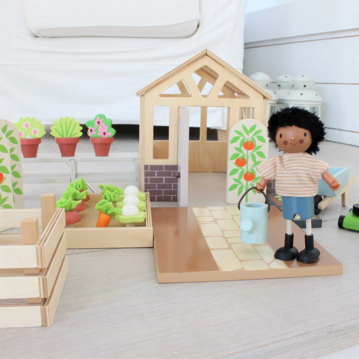 Tender Leaf greenhouse with open door, miniature vegetable bed and a doll holding the watering can