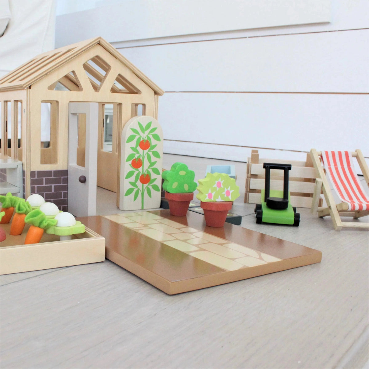 Tender Leaf wooden greenhouse with tomato shrub, potted plants, miniature lawnmower and striped deck chair