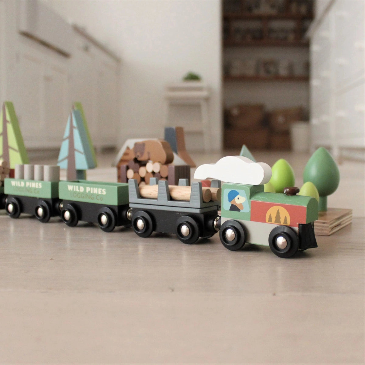 Wooden toy train set with animal figures and nature-themed cars on a wooden floor.