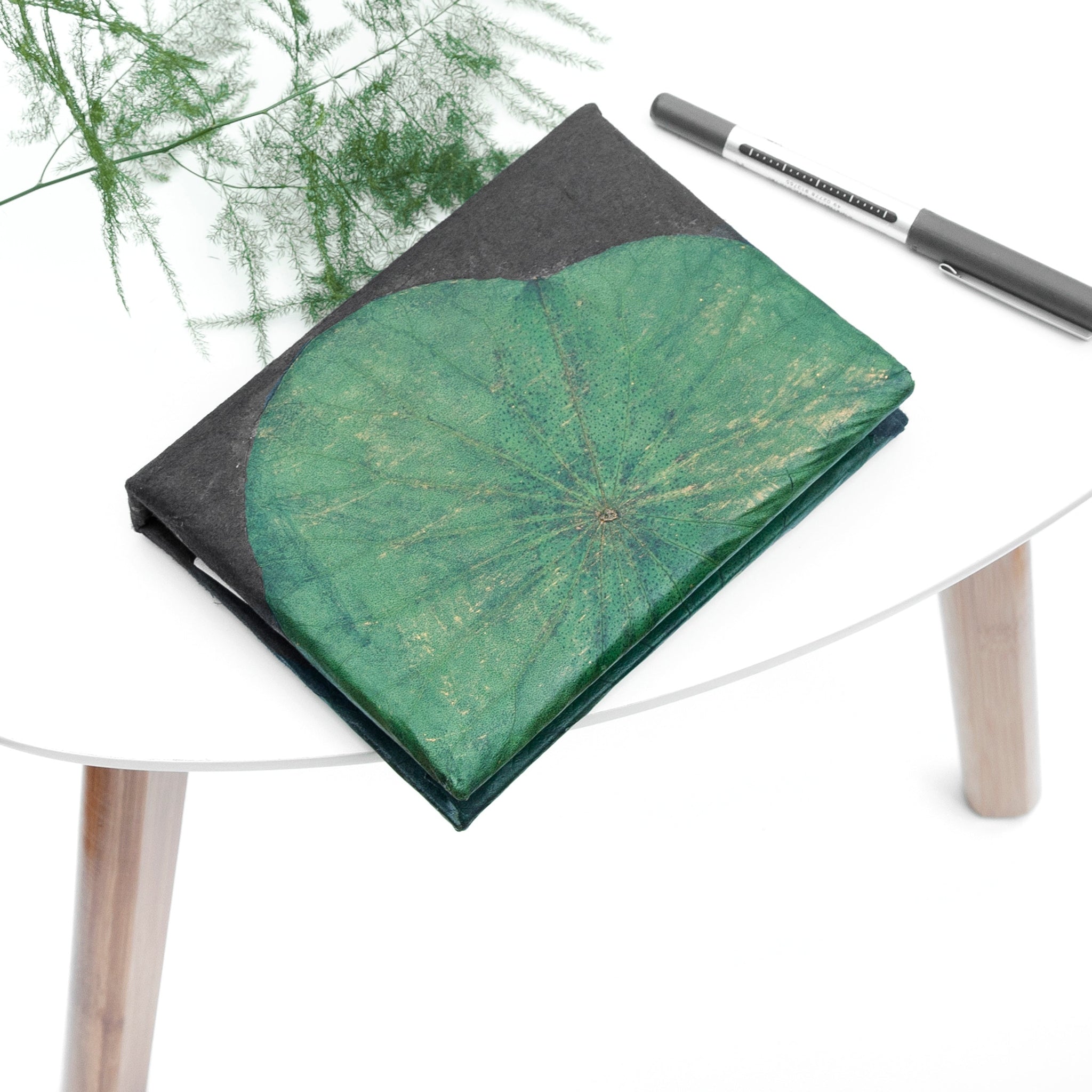 Notebook with green leaf design on a white surface