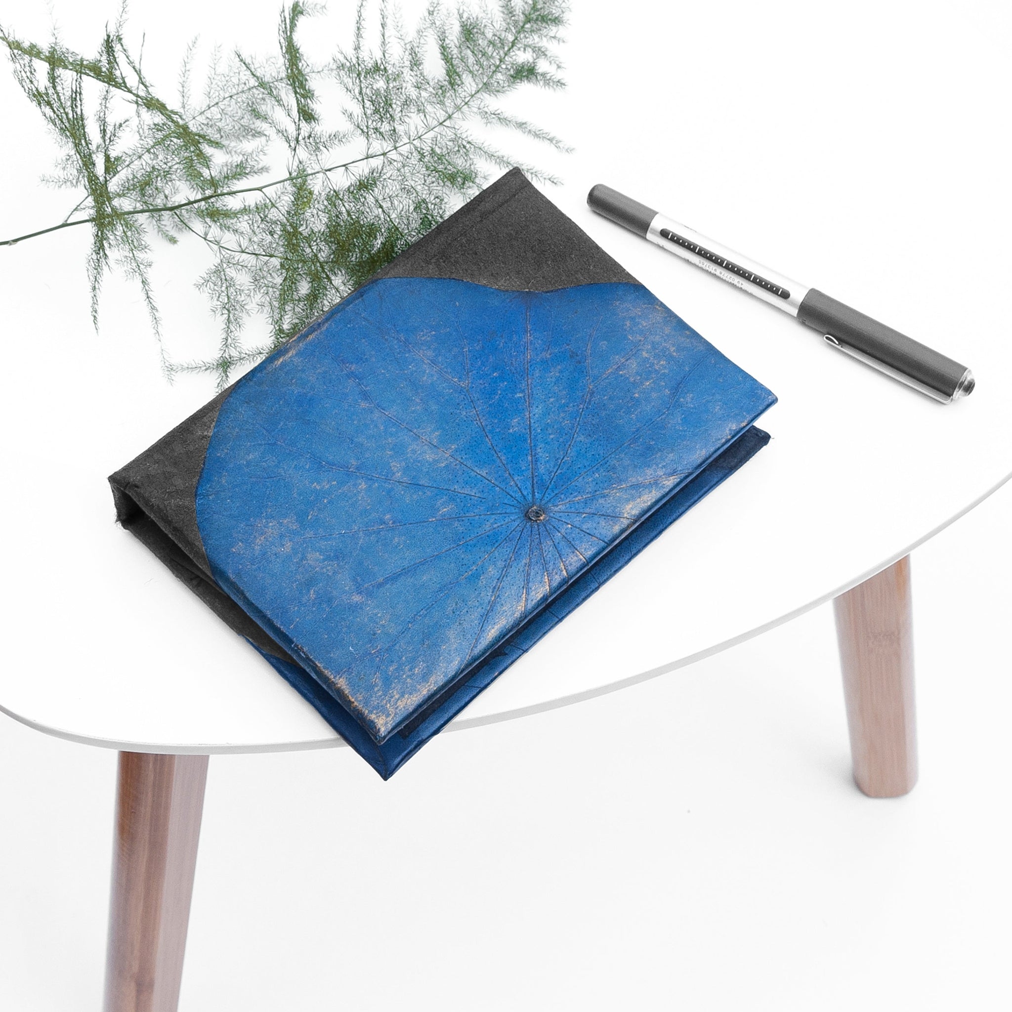 Blue note book with a pen on a white table
