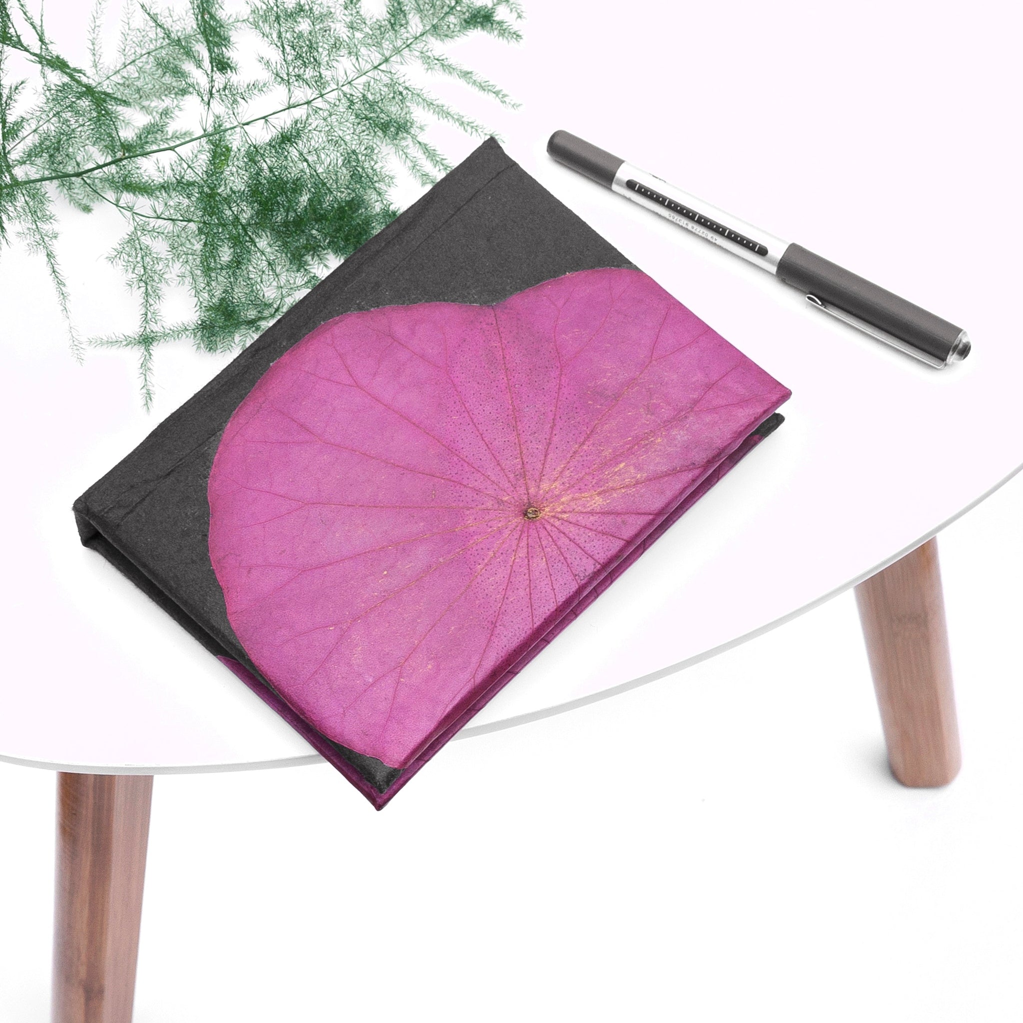 Purple notebook on a white table with a pen next to it