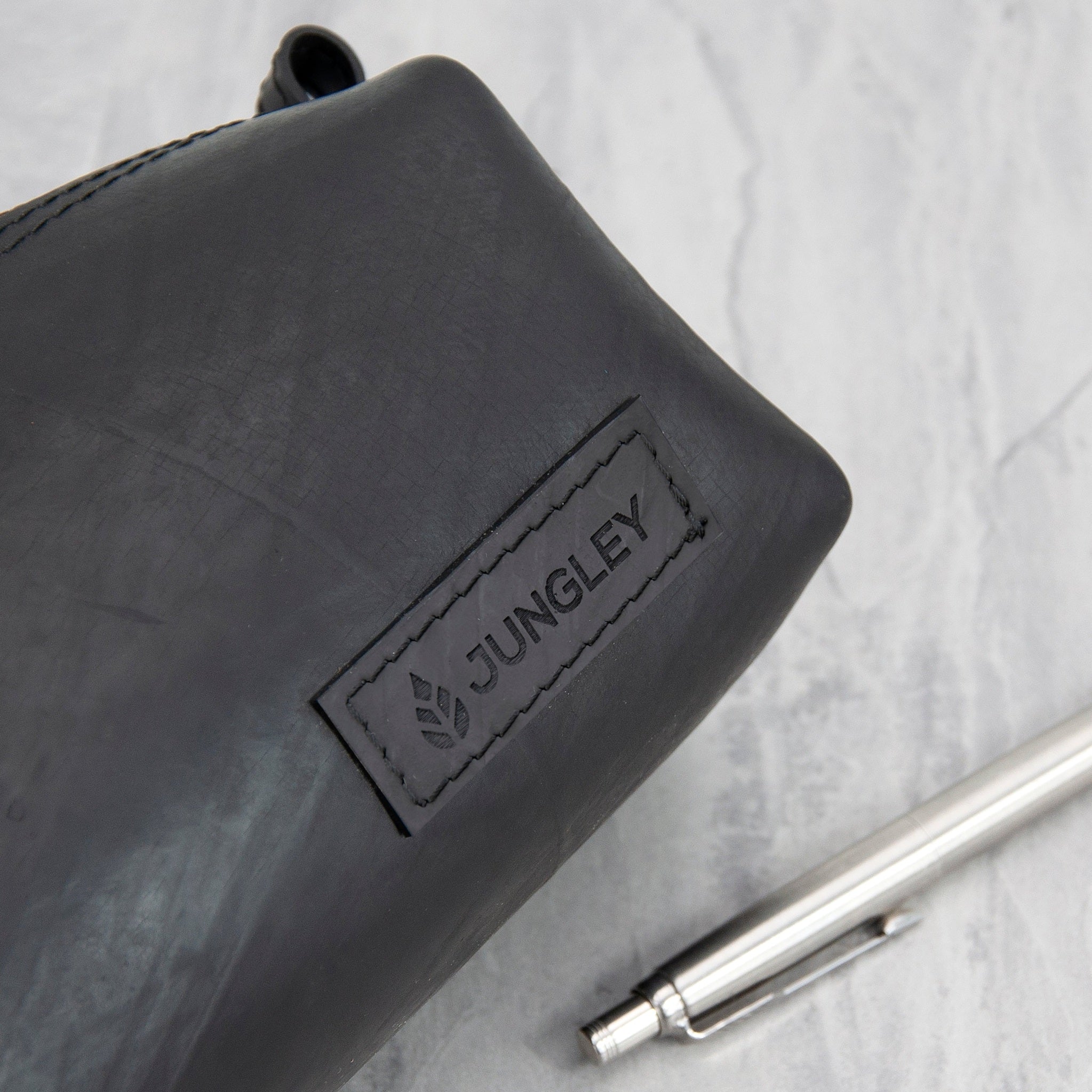 Black recycled rubber pencil case with 'Jungley' branding on a light grey background