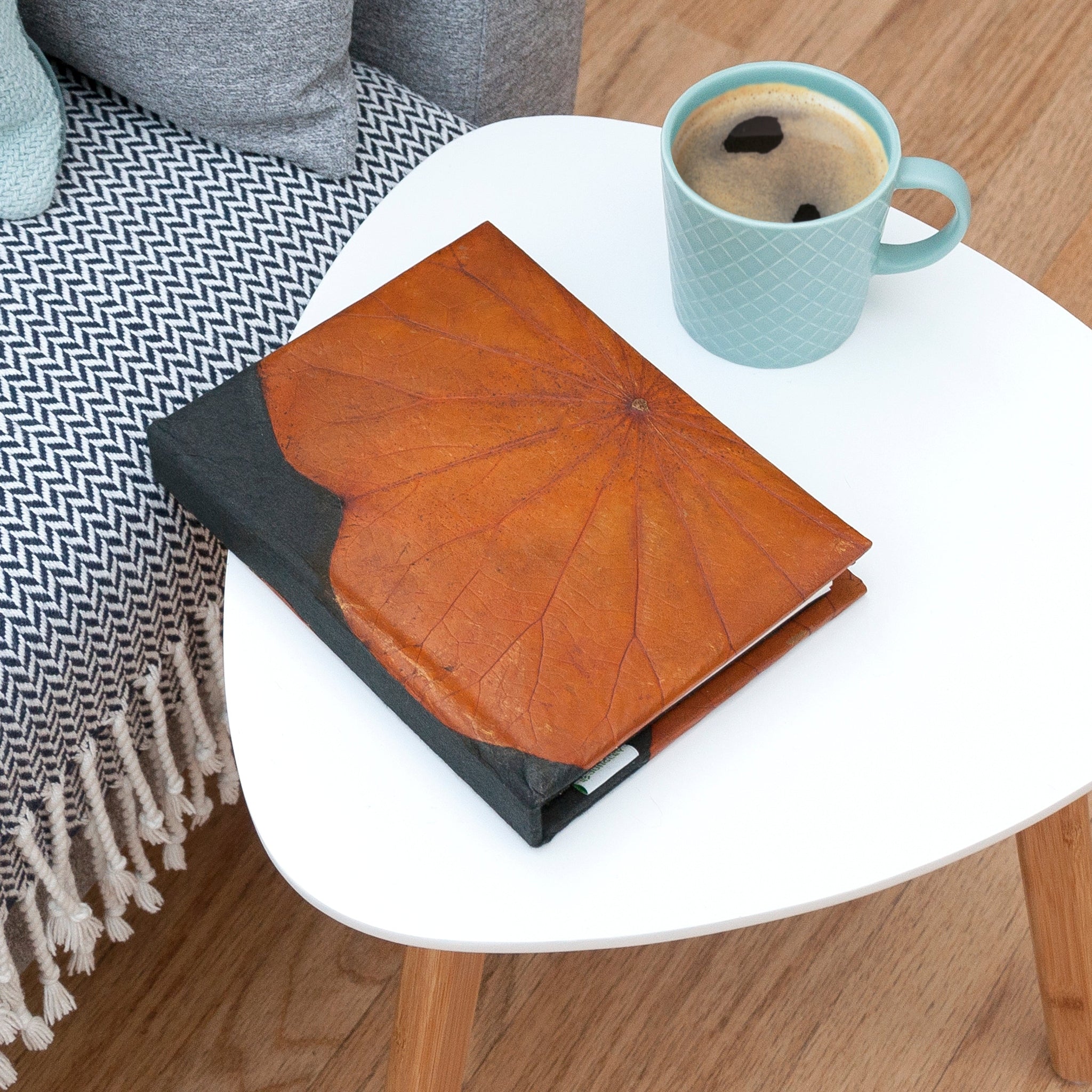 Brown notebook and blue mug with coffee on a white table