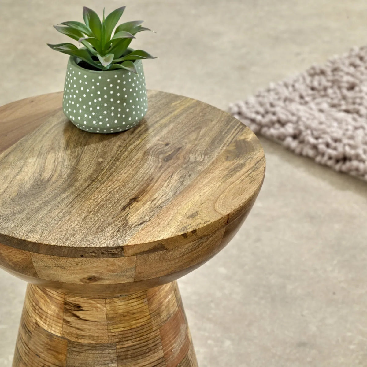 Wooden side table with a small potted plant on a neutral background
