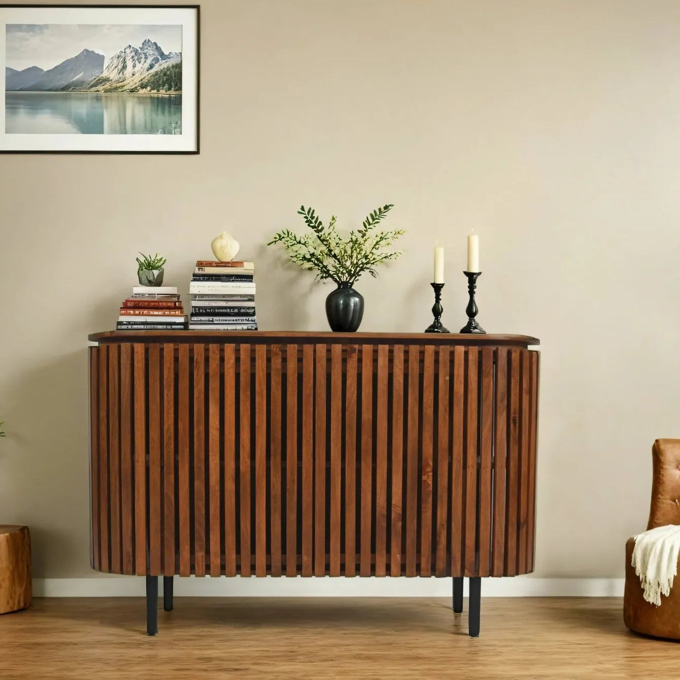 Wooden sideboard with decorative items in a room with a mountain landscape painting.