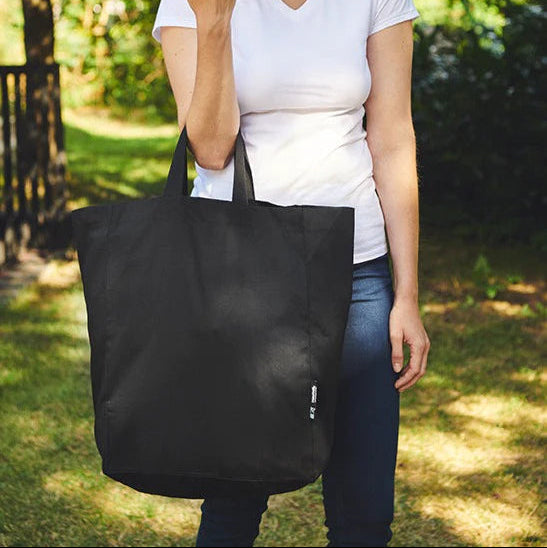Model carrying the black Fairtrade Organic Twill Grocery Bag outdoors, showing its size