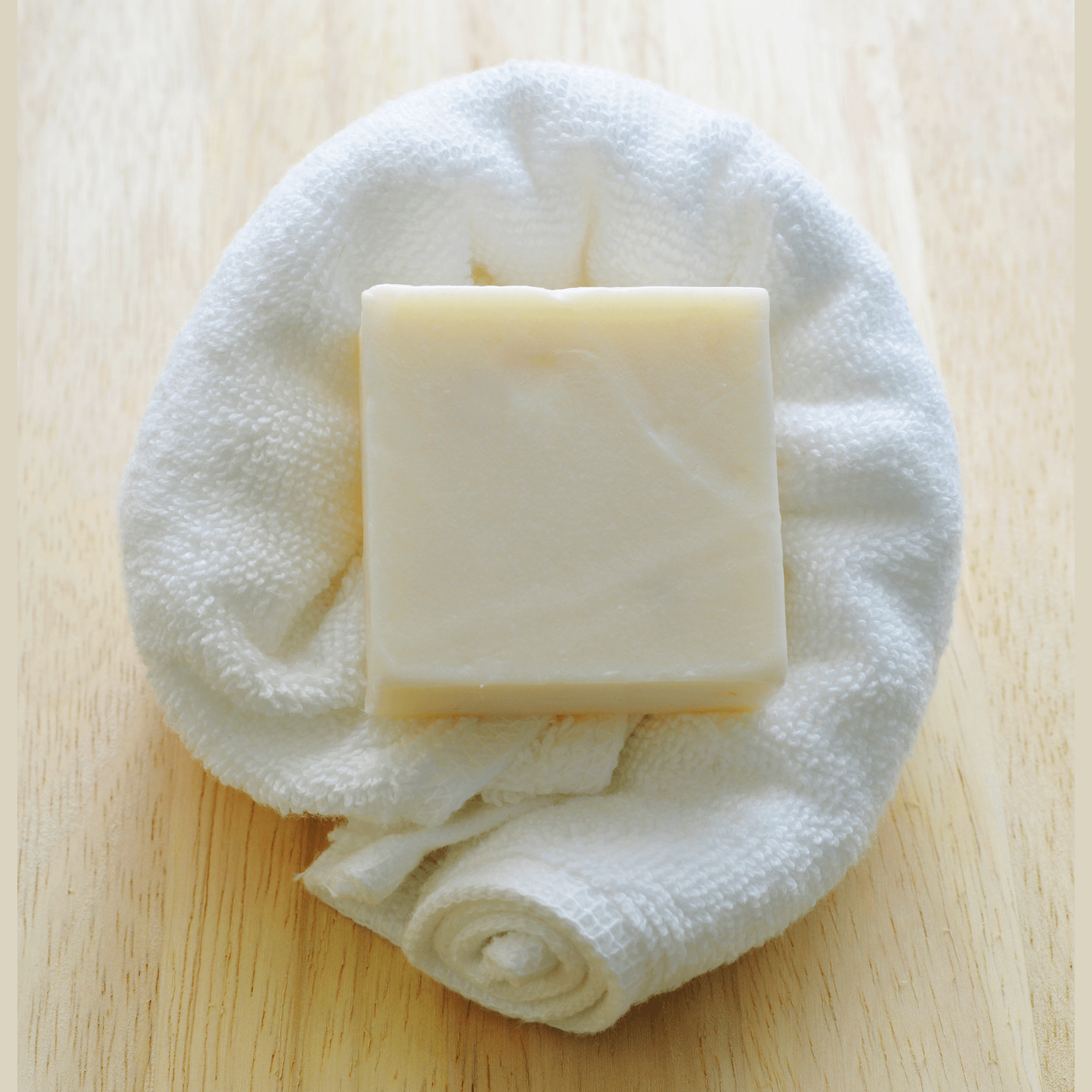 Bar of natural hair conditioner on a white towel on a wooden surface.