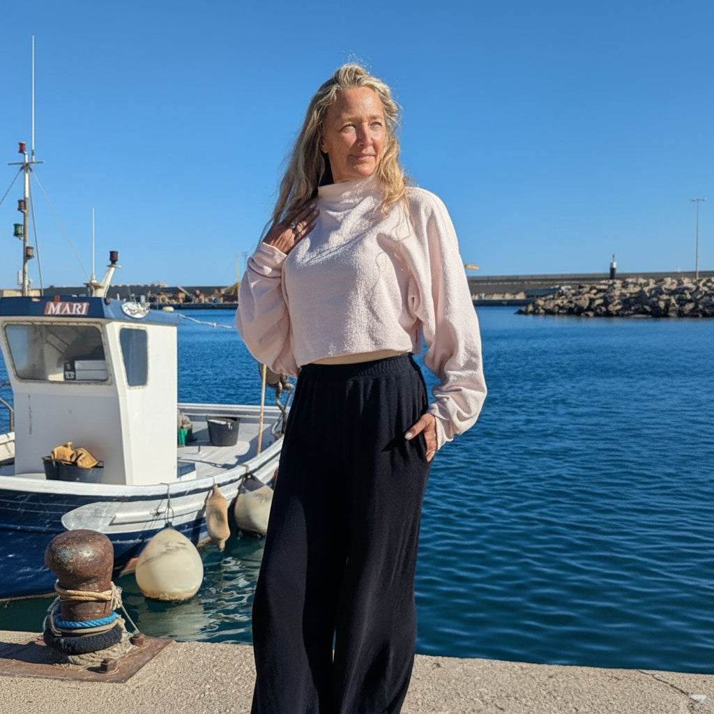 Woman standing by a harbor with boats and clear blue water