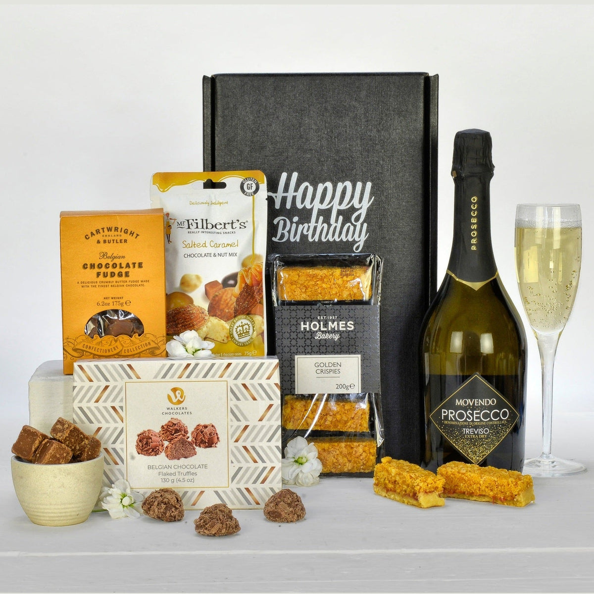 Birthday gift box with snacks, chocolates, and a bottle of prosecco on a white background