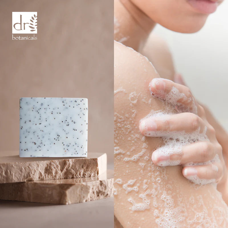 Soap bar with 'dr botanicals' branding on a stone platform, next to a person washing their hands with soap.