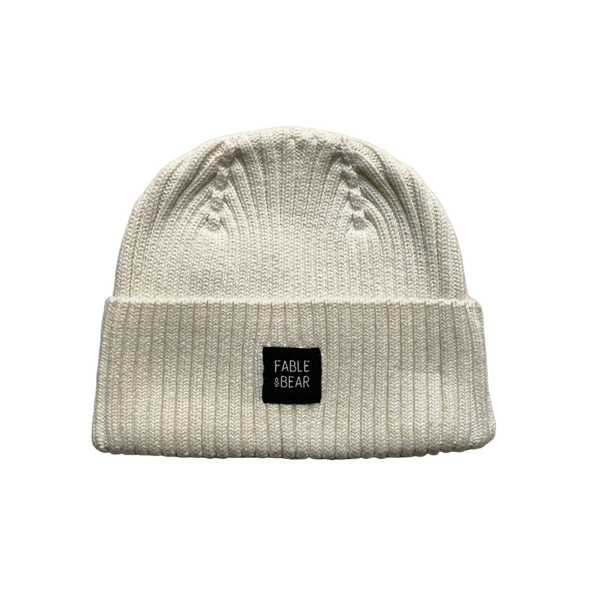 An off-white ribbed knit beanie hat with a small black square patch on the front that reads 'FABLE & BEAR'.