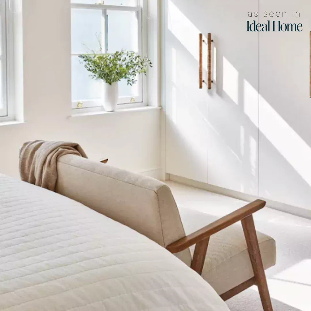 Long Dunstanburgh rattan handles fitted vertically to white wardrobe doors in a bright bedroom