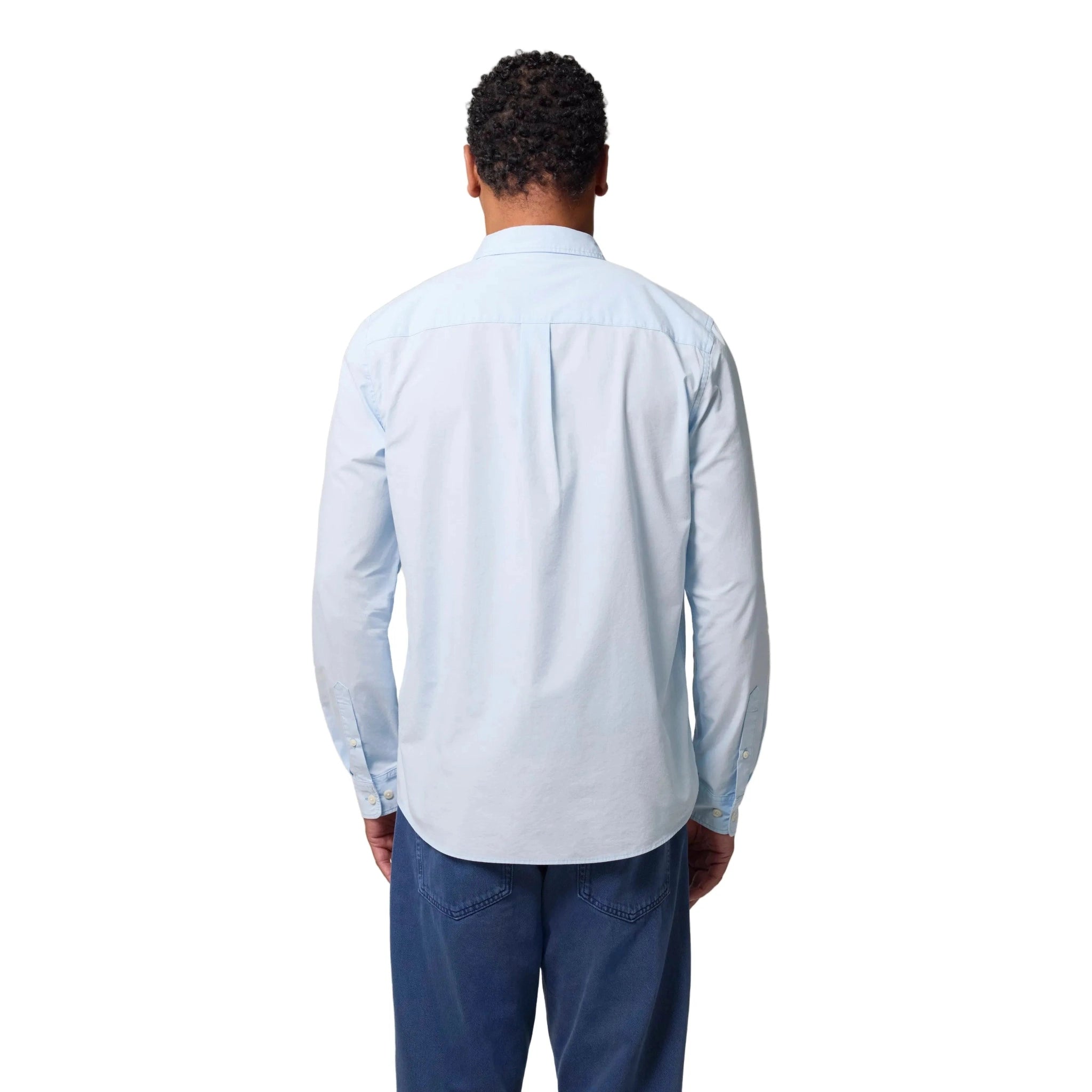 Person wearing a light blue button-up shirt and dark pants on a white background