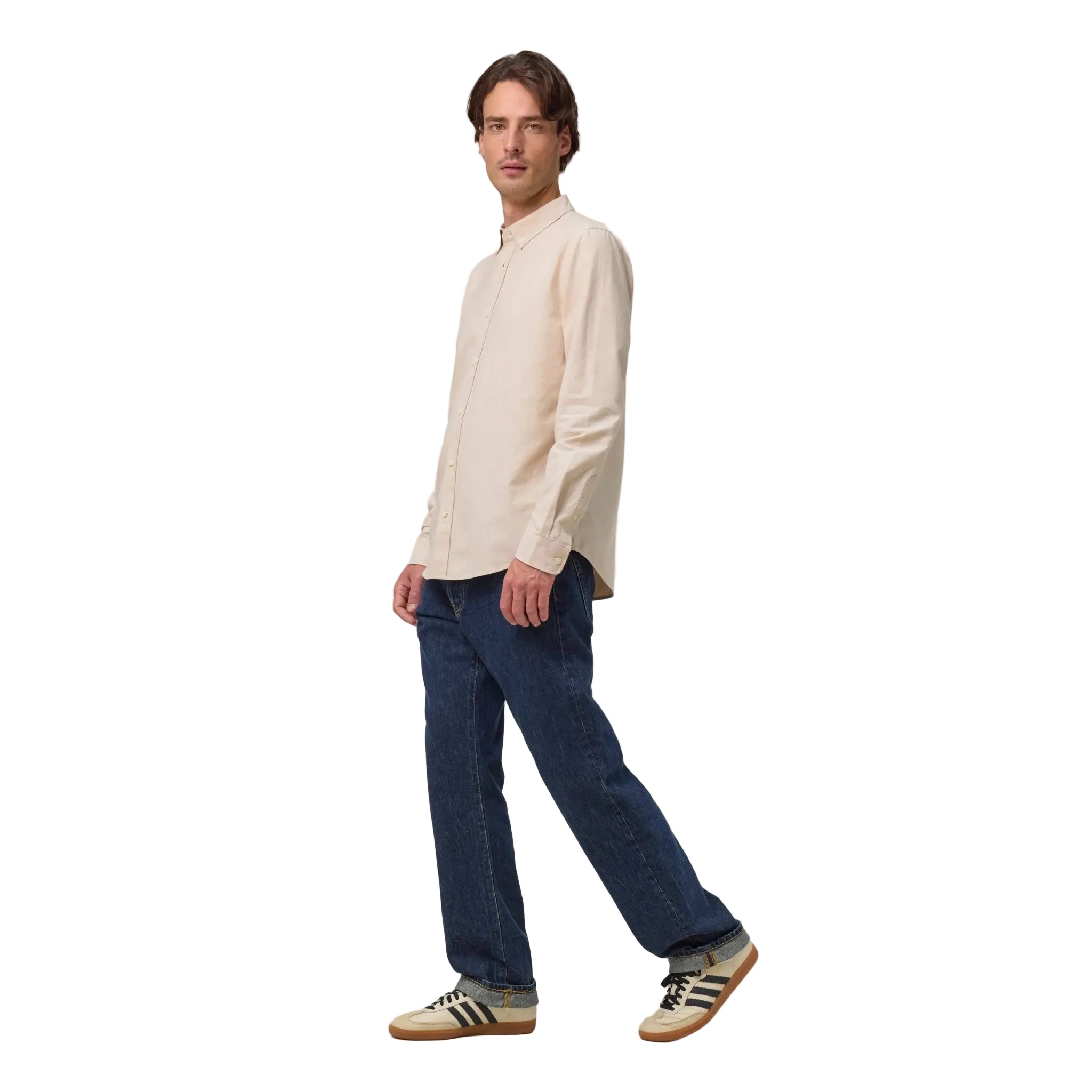 Man wearing a beige shirt and blue jeans on a white background